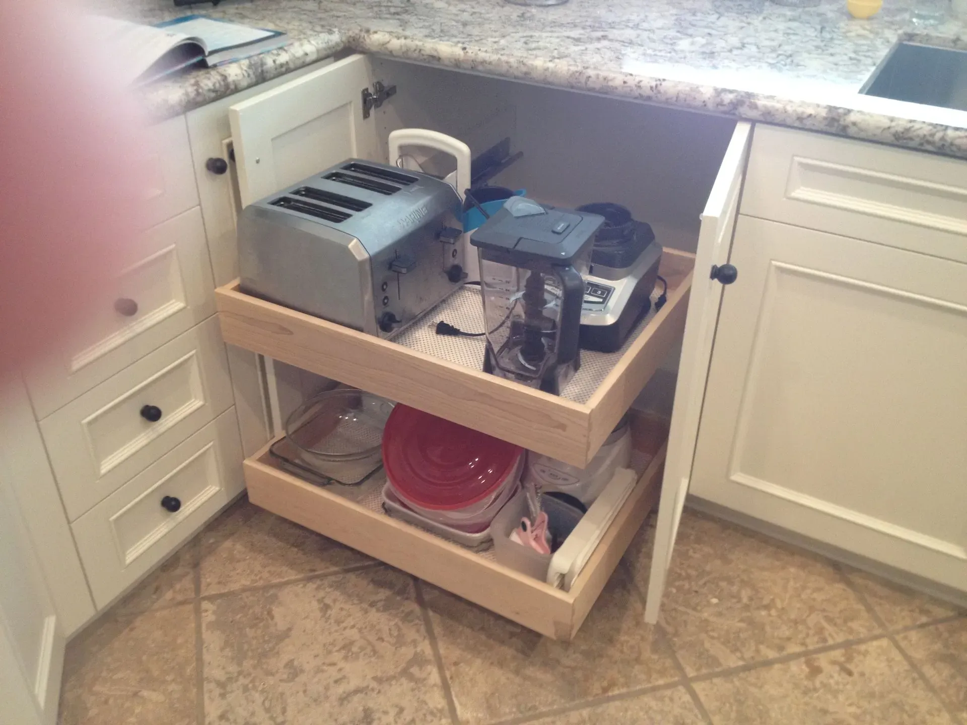 Kitchen corner with a pull-out shelf holding appliances and storage bins under the counter