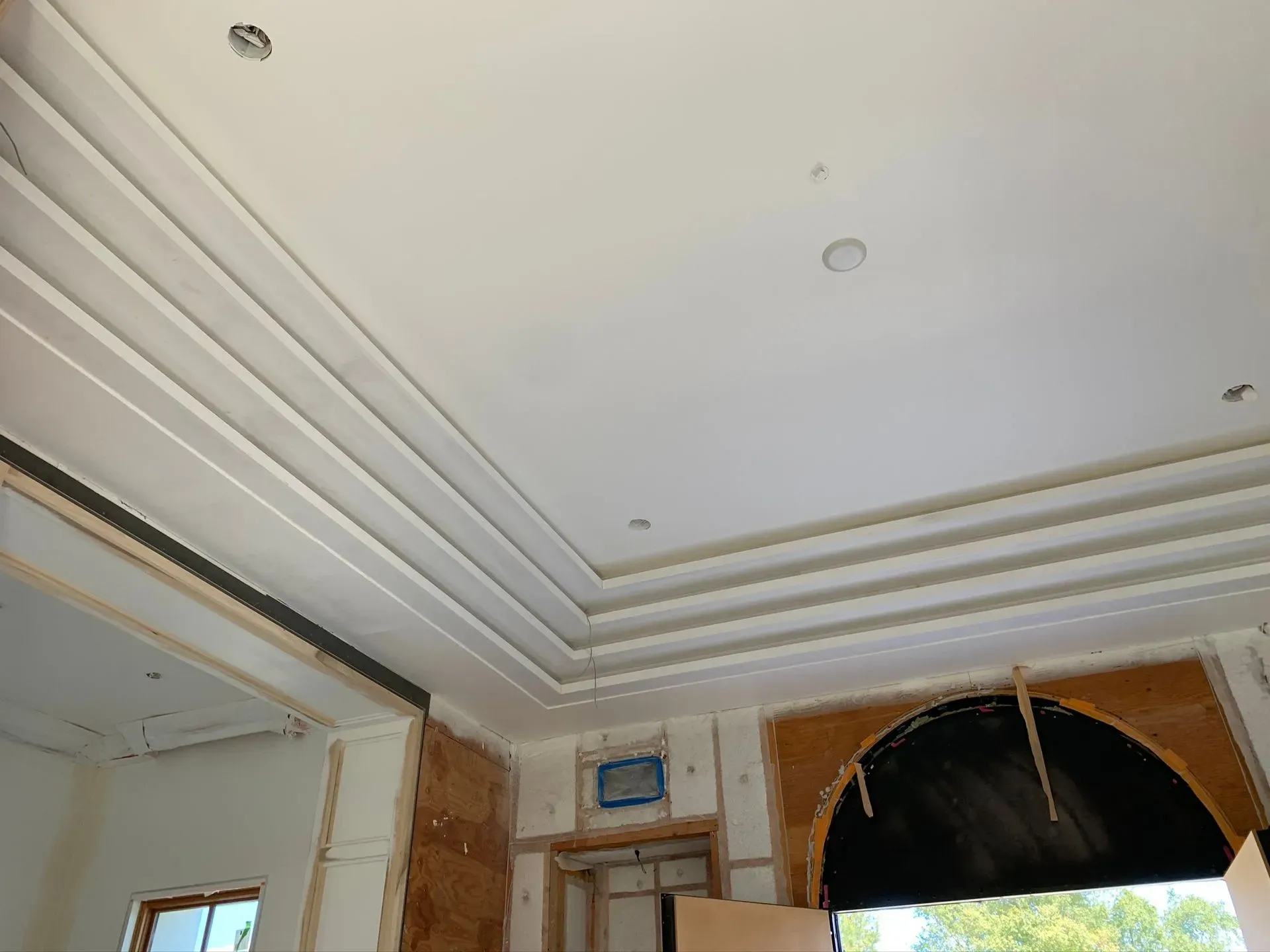 Ceiling interior with layered molding, recessed lights, and a window opening under construction