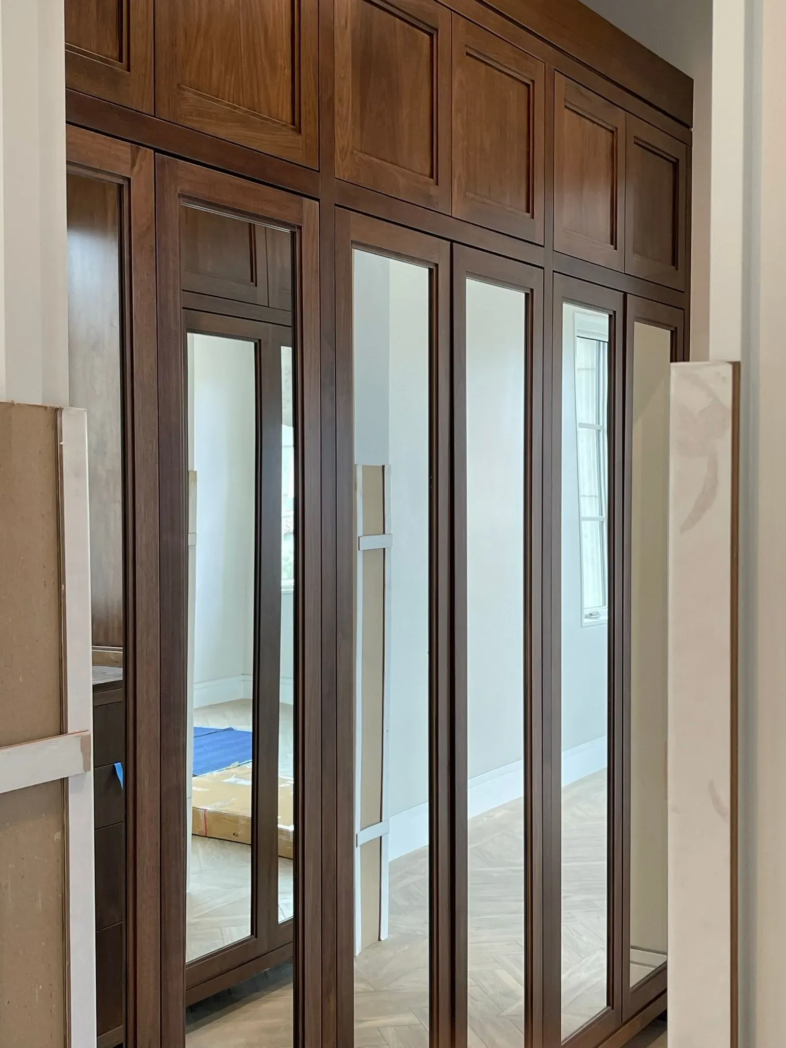 Wooden wardrobe with mirrored doors and glass panels in a bright bedroom
