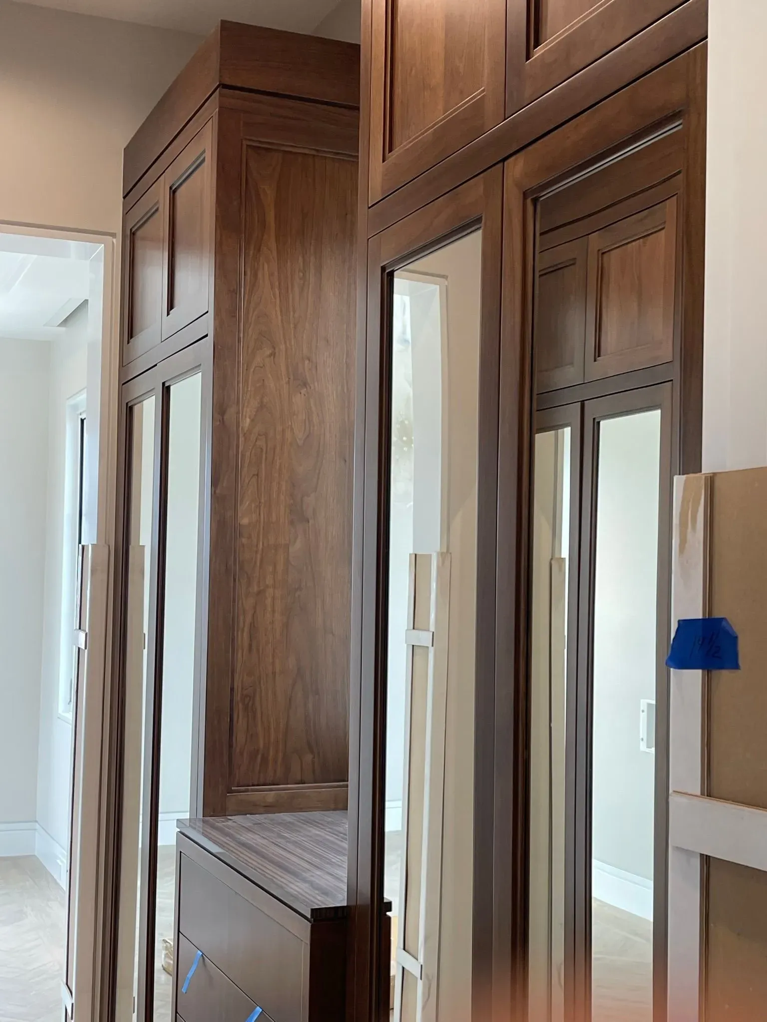 Wooden built-in wardrobes with mirrored doors in a bright hallway or dressing area.
