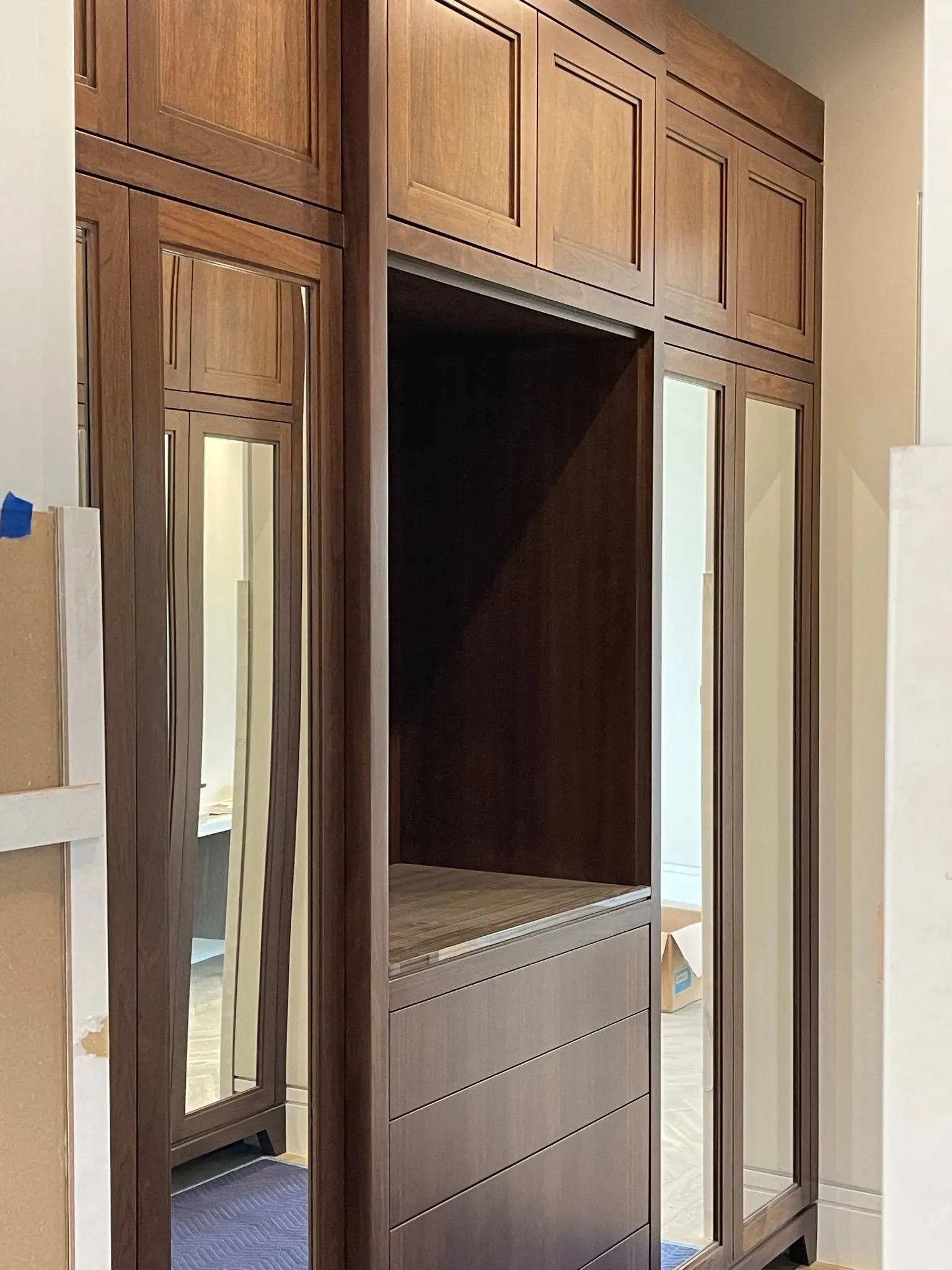 Wooden built-in wardrobe with mirrored side doors and an open central closet compartment.