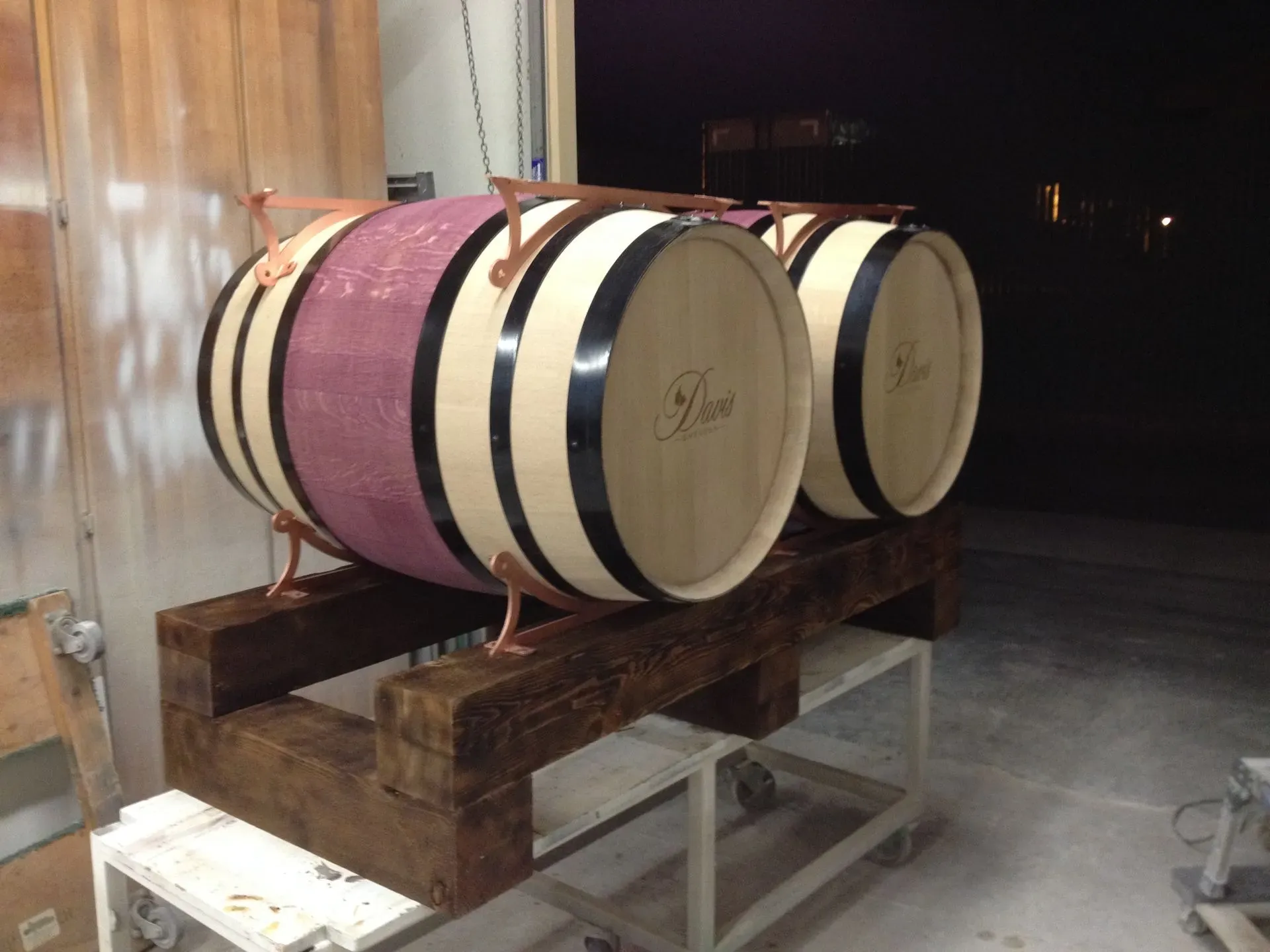 Two wooden barrels on a wheeled pallet in a dim storage area