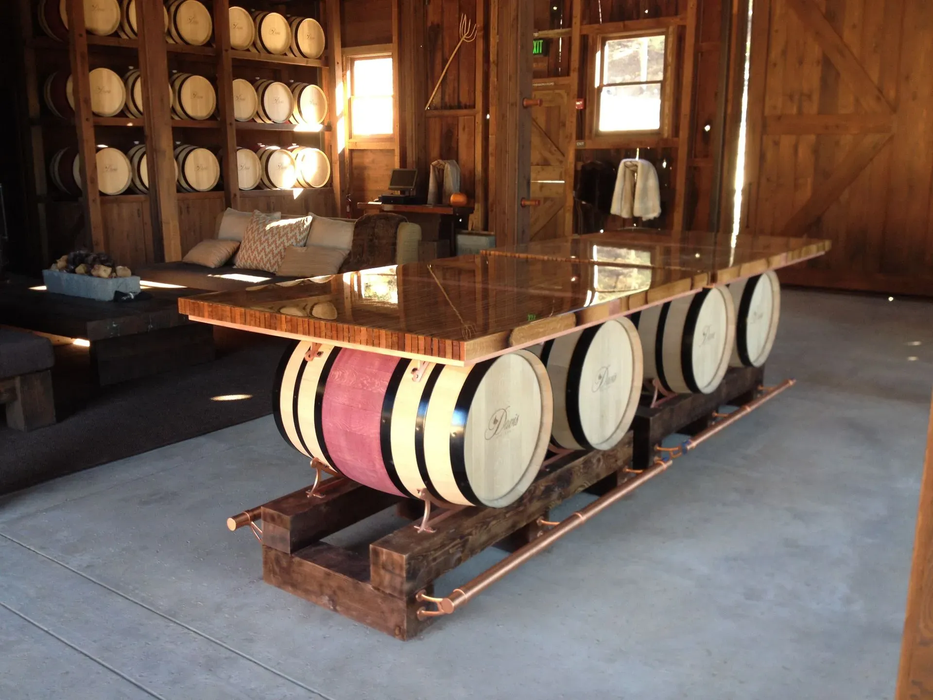 Wooden wine barrel table in a rustic room with barrel-styled stools and warm sunlight through windows