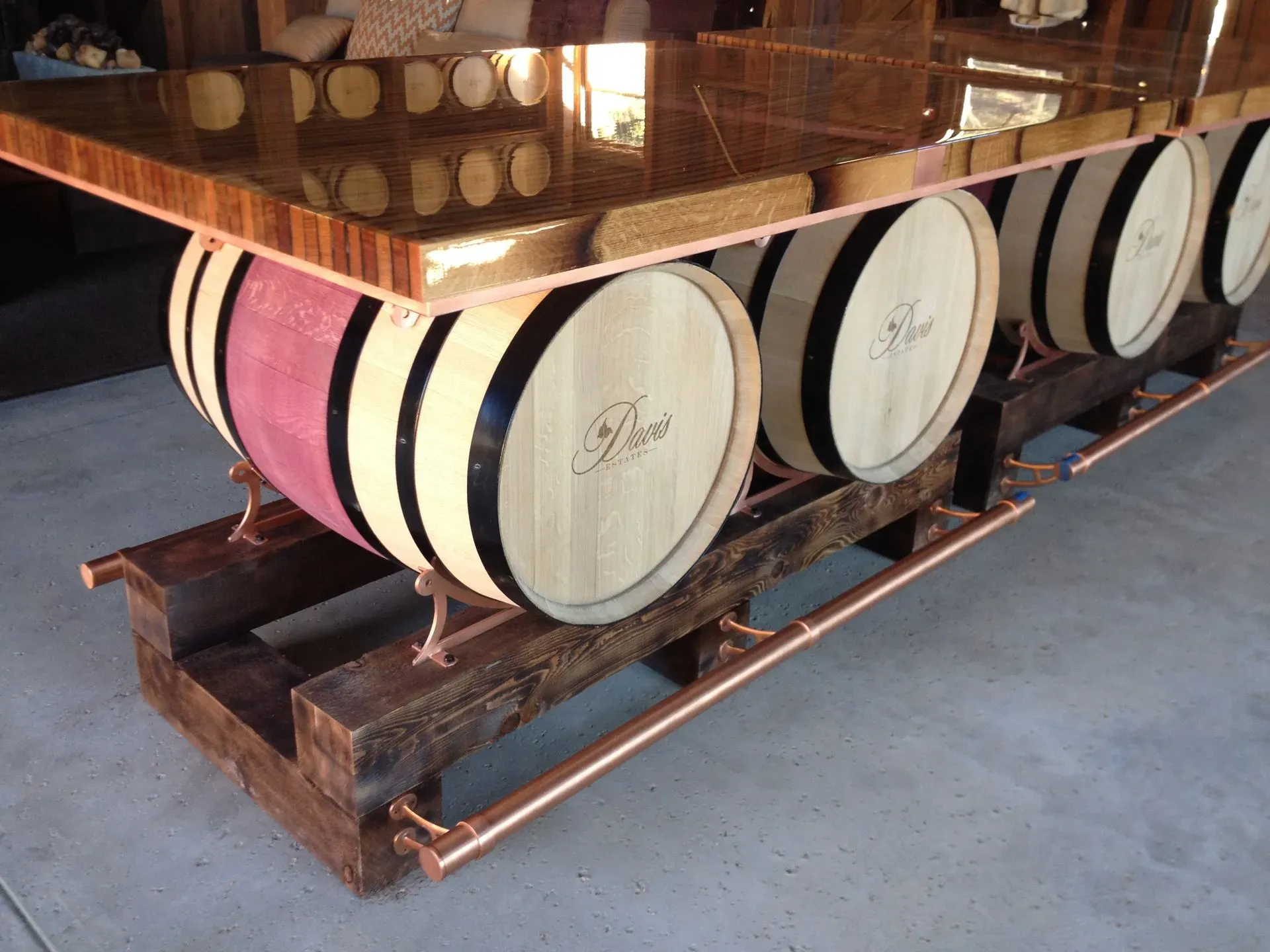 Wooden cart displaying large wine barrels with white and pink ends in a cellar or warehouse