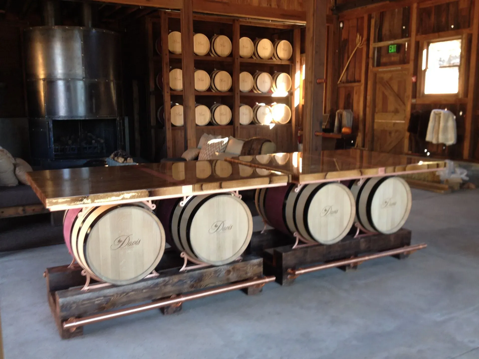 Rustic wine cellar with stacked barrels and a row of oak barrels used as a table base