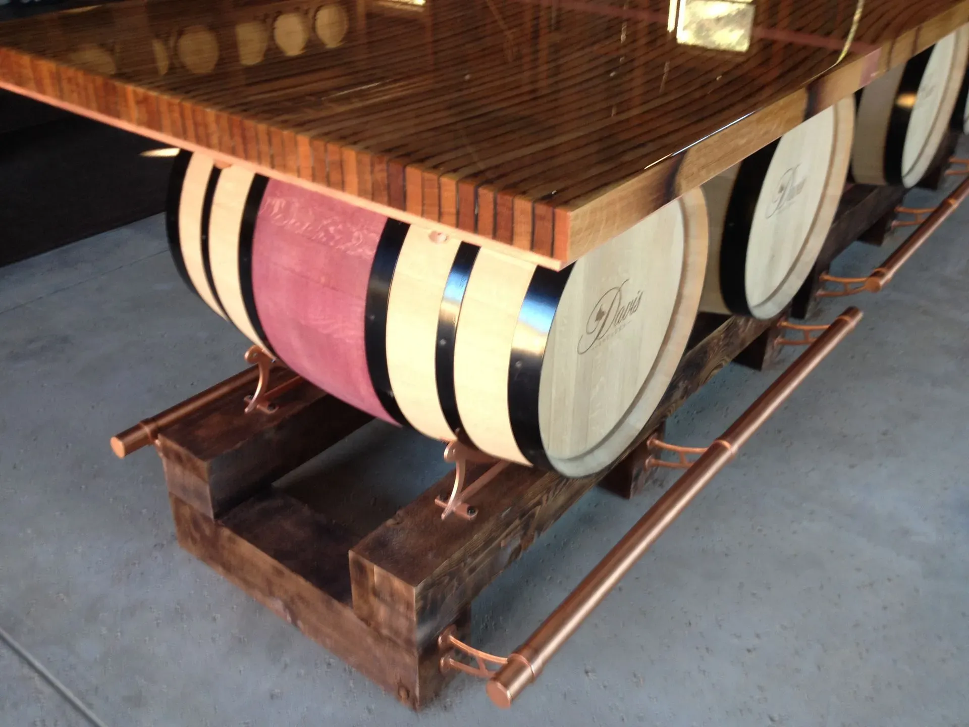 Wooden table with large decorative barrel-like legs in pink, cream, and black stripes