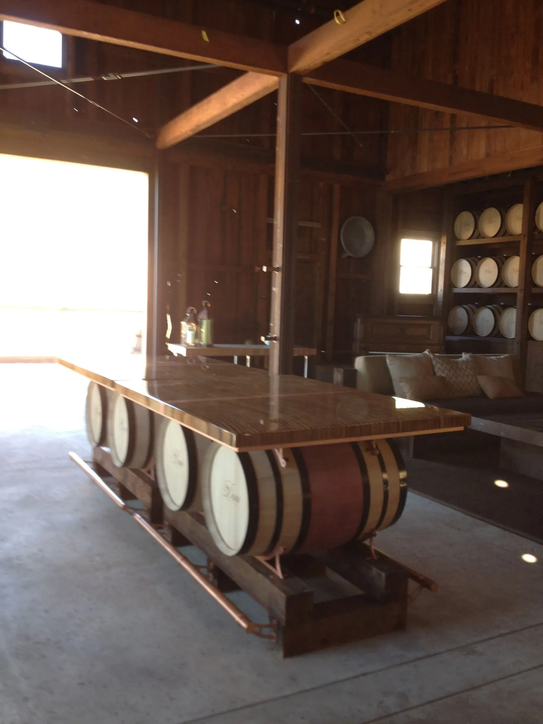 Wooden cabin interior with a long table made from wine barrels and a shelf of plates in the background
