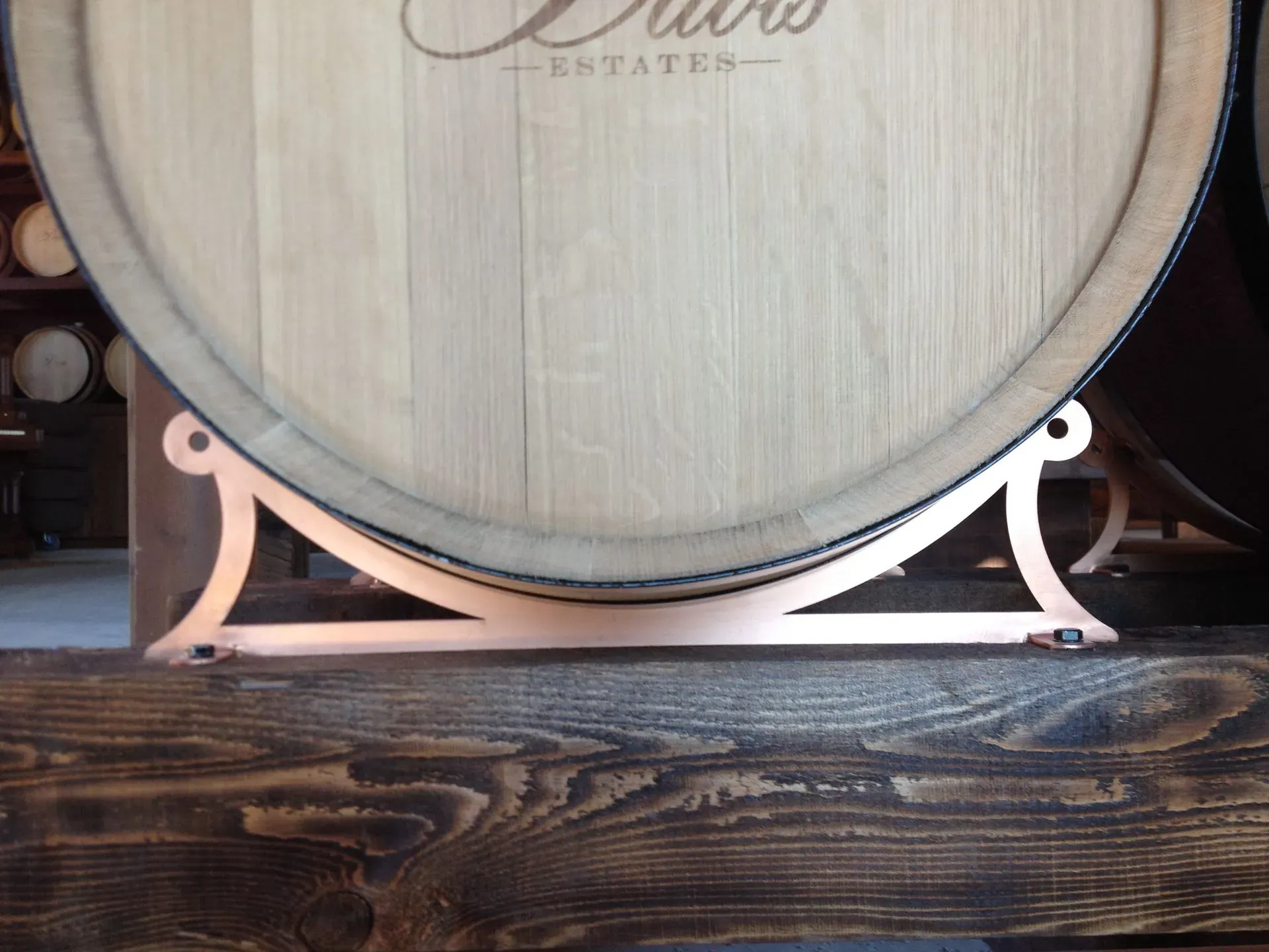 Wooden wine barrel on copper stand against a rustic dark wood floor