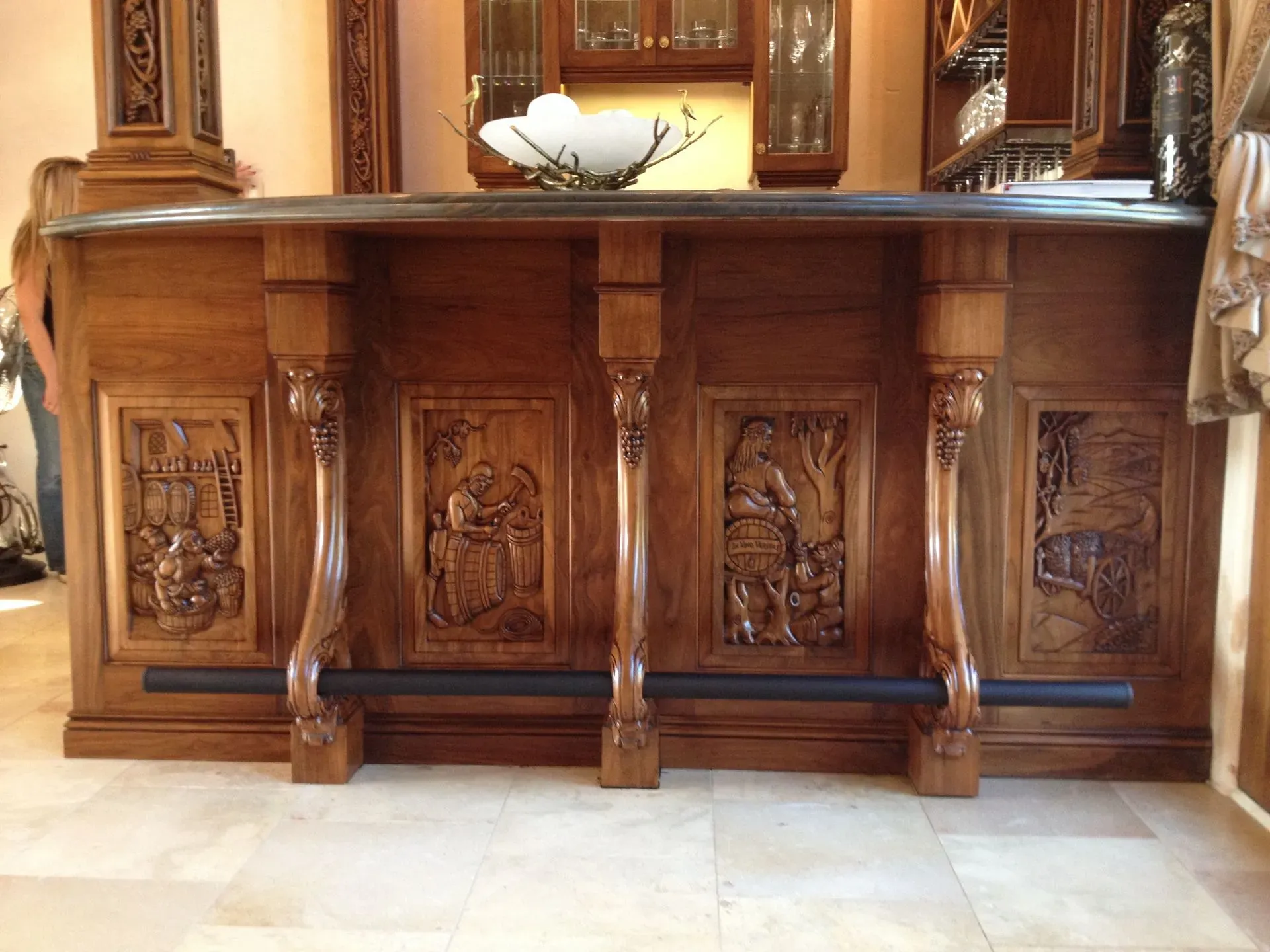 Ornate wooden bar counter with carved panels in a warmly lit room