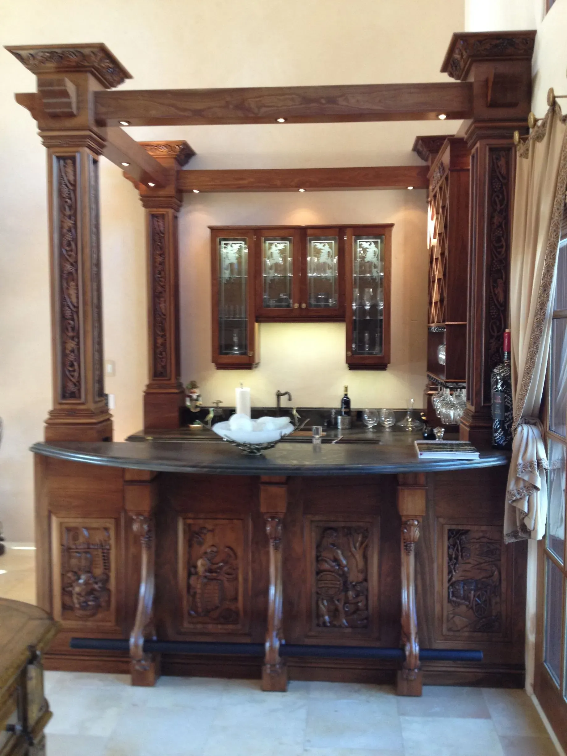 Wooden bathroom vanity with mirror, sink, and ornate carved cabinets in a warm-toned interior