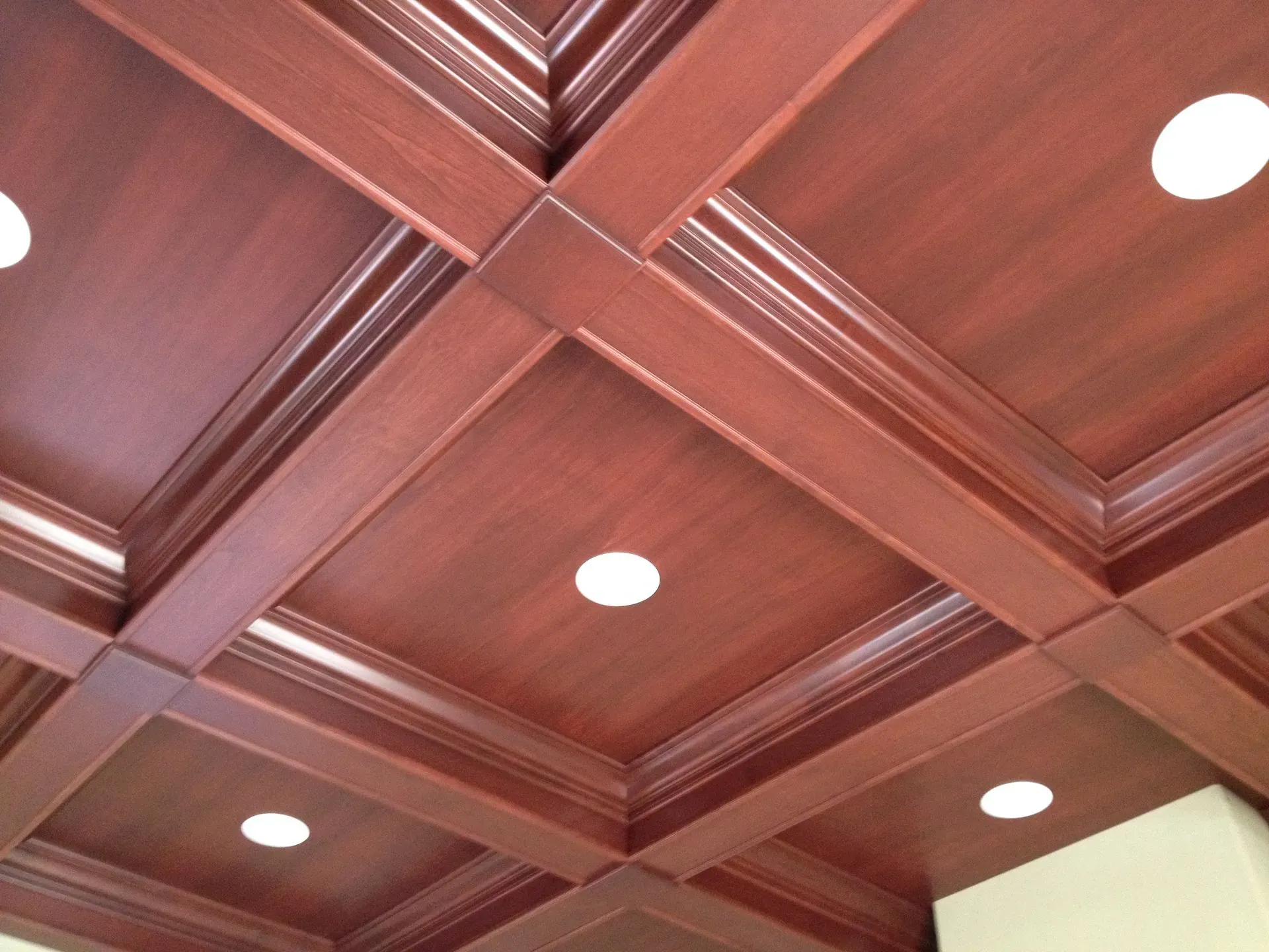 Wood-paneled coffered ceiling with recessed lights and decorative molding