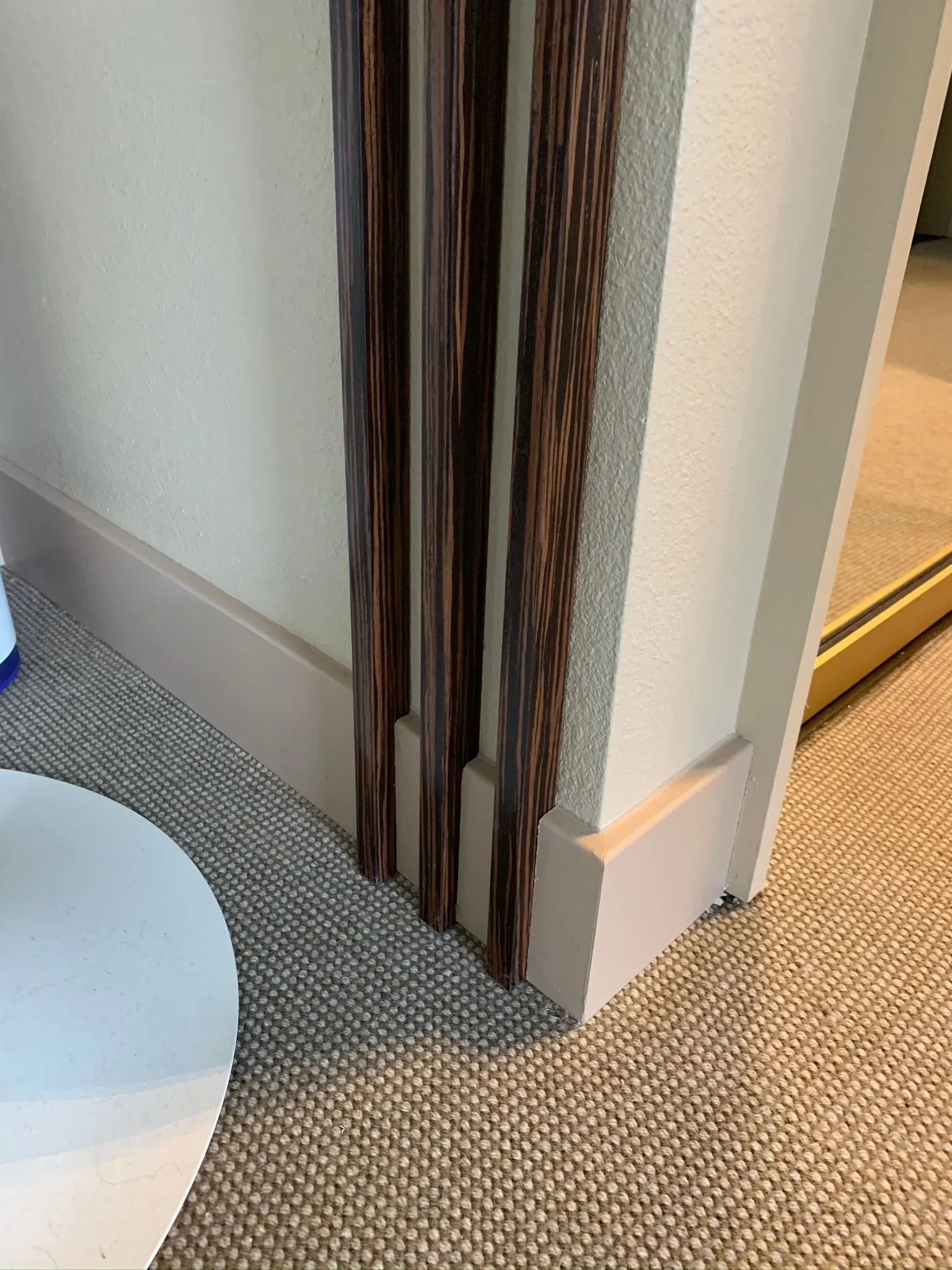 Carpeted corner with wood trim and a partial white round table on the left