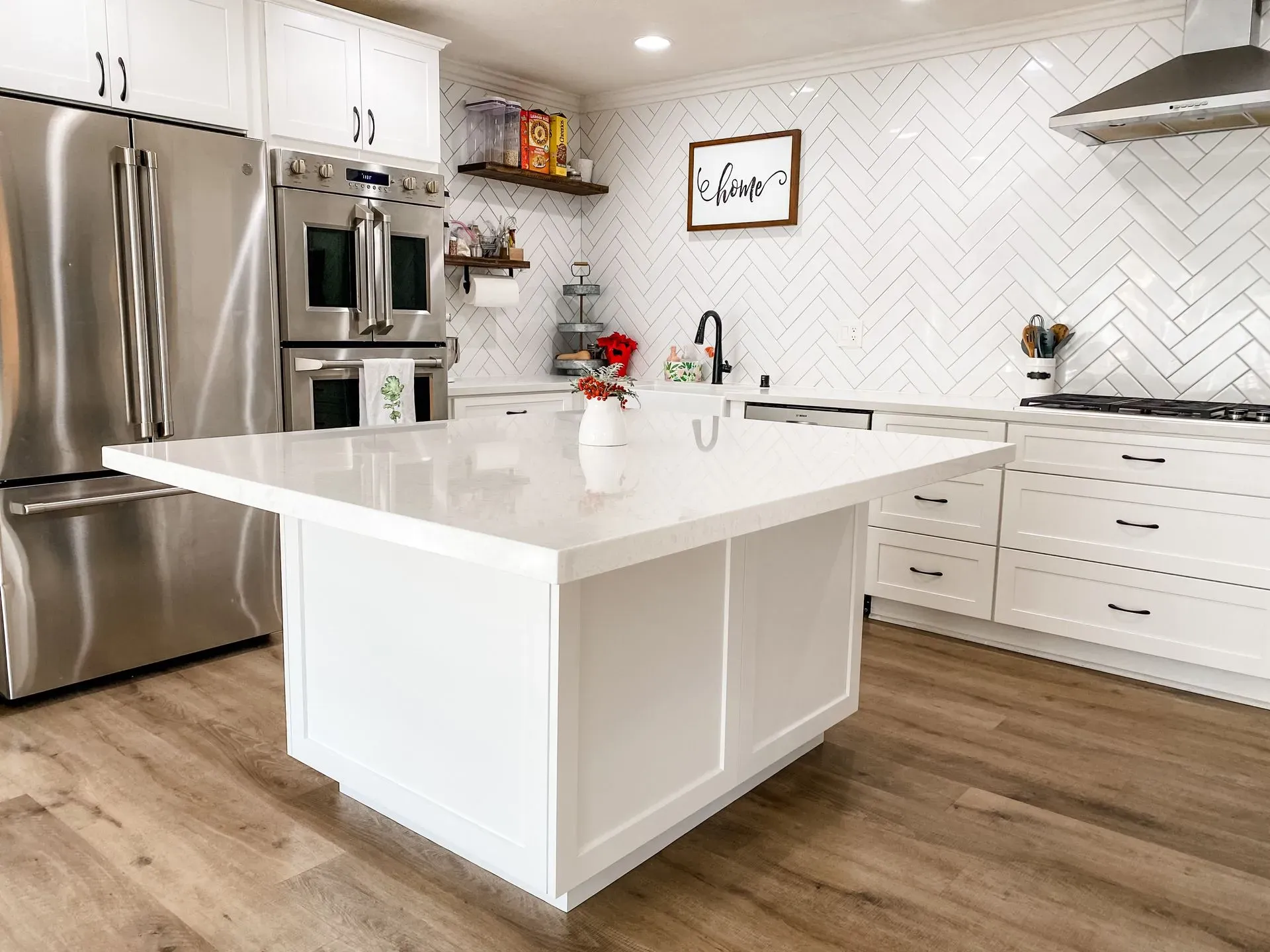 Bright modern kitchen with white cabinets, stainless steel appliances, and a large white island