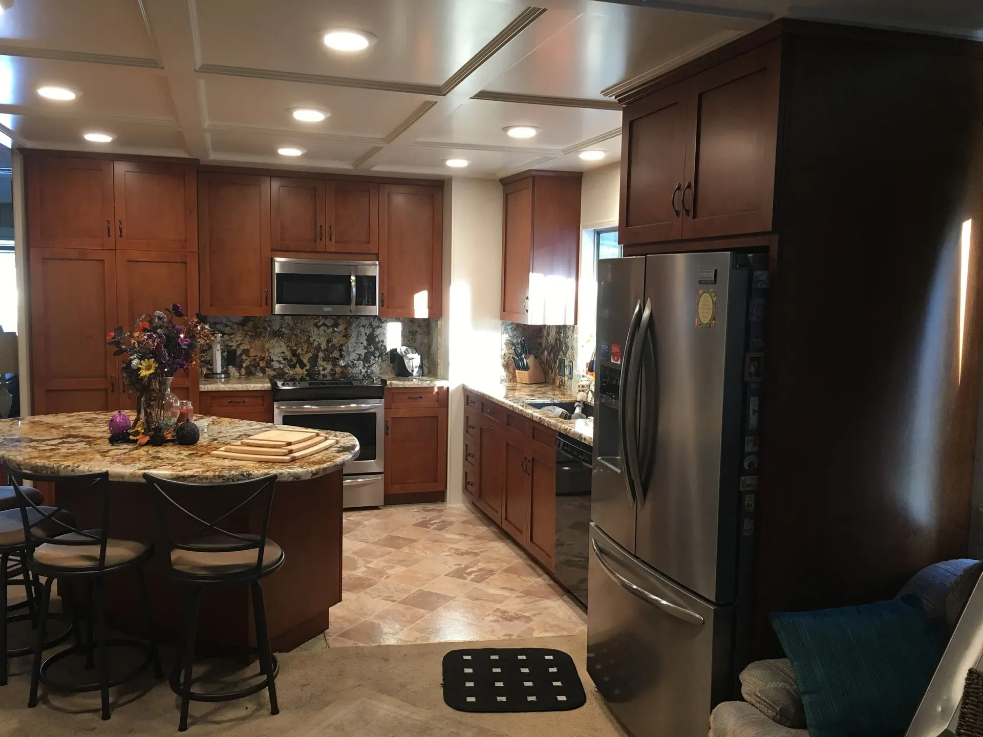 Modern kitchen with dark wood cabinets, stainless steel appliances, and a round island table with stools