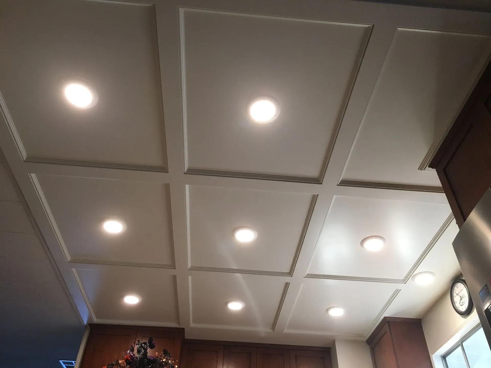Ceiling with recessed square panels and lit recessed lights in a room