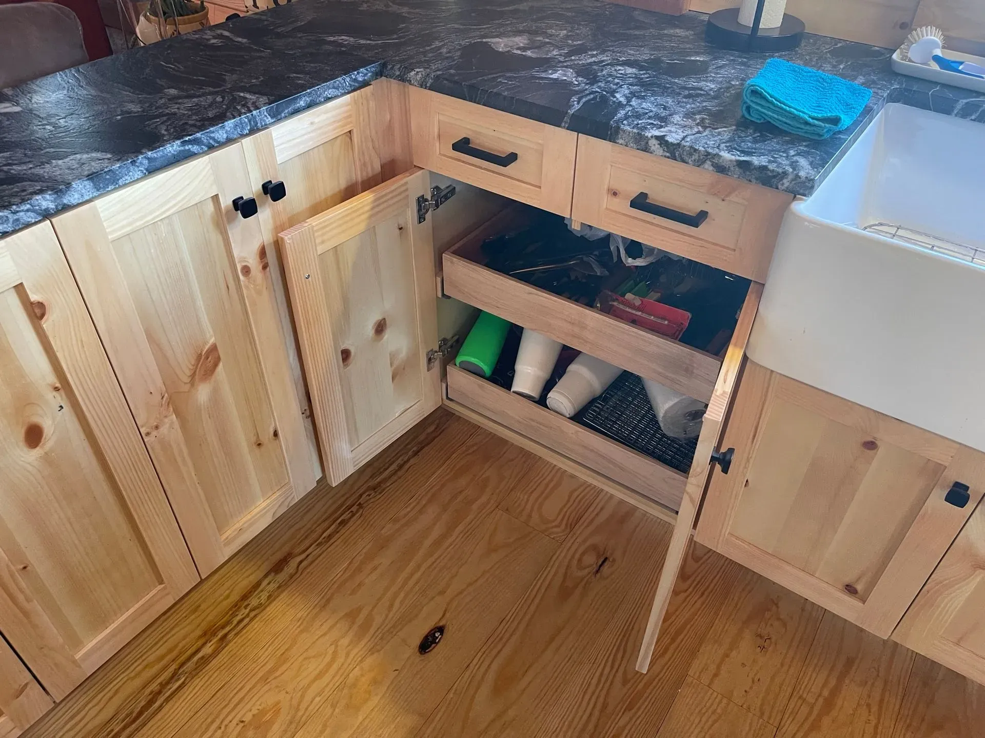 Open kitchen cabinet under a countertop, revealing stored bags and items inside.