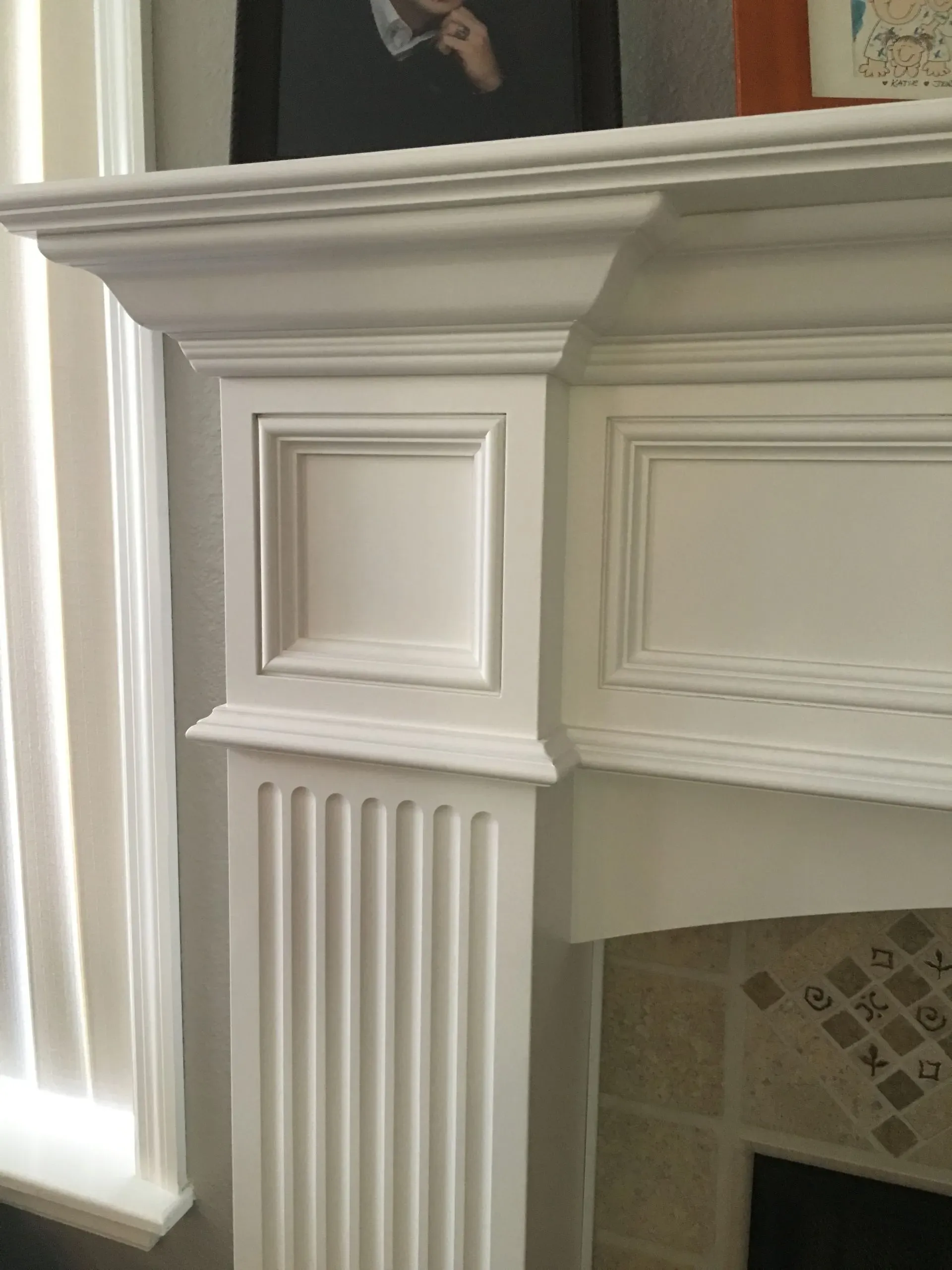 White decorative fireplace mantel with fluted columns and tiled inset in a room