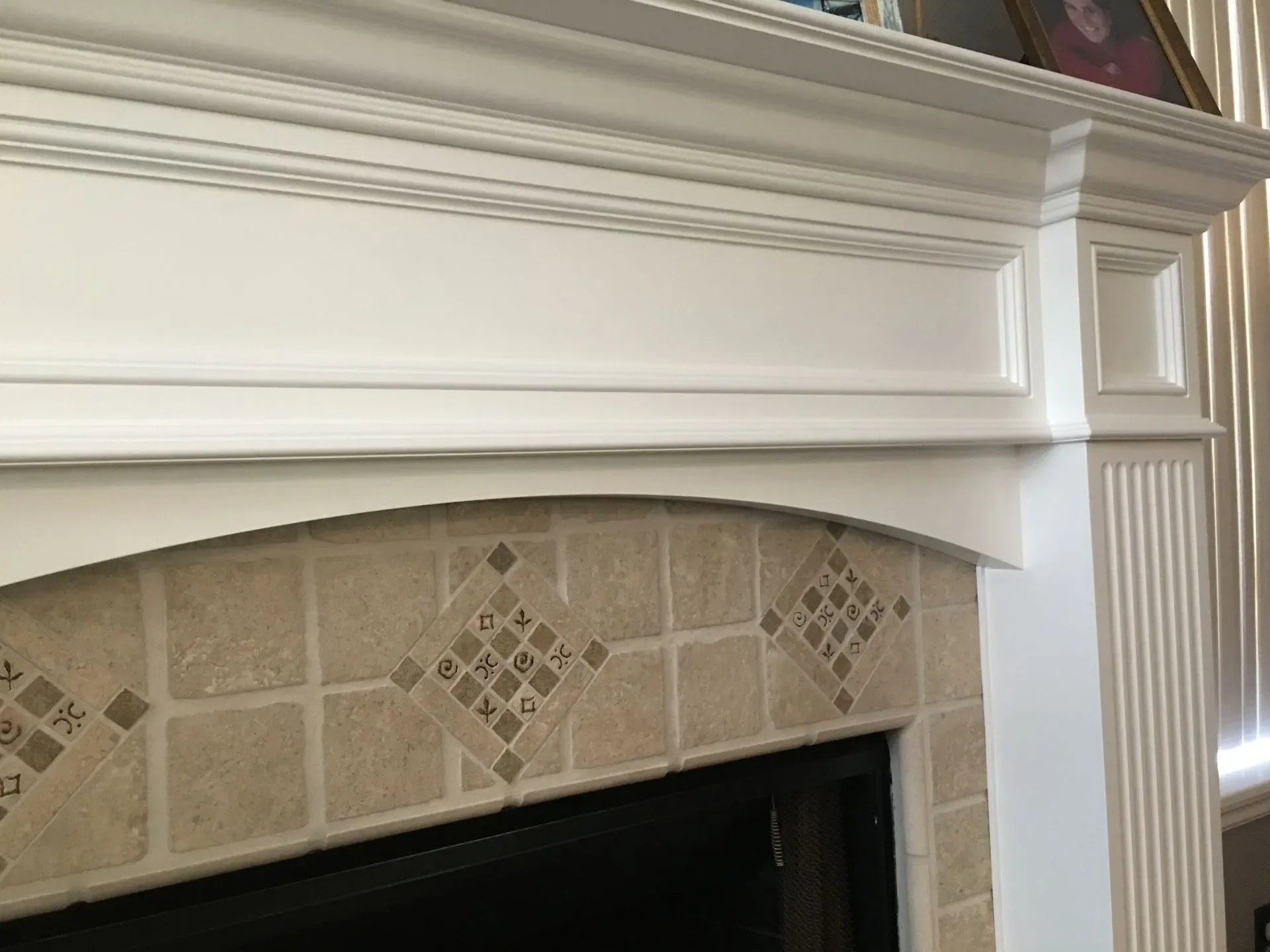 White mantel and decorative tile surround above a fireplace in a living room
