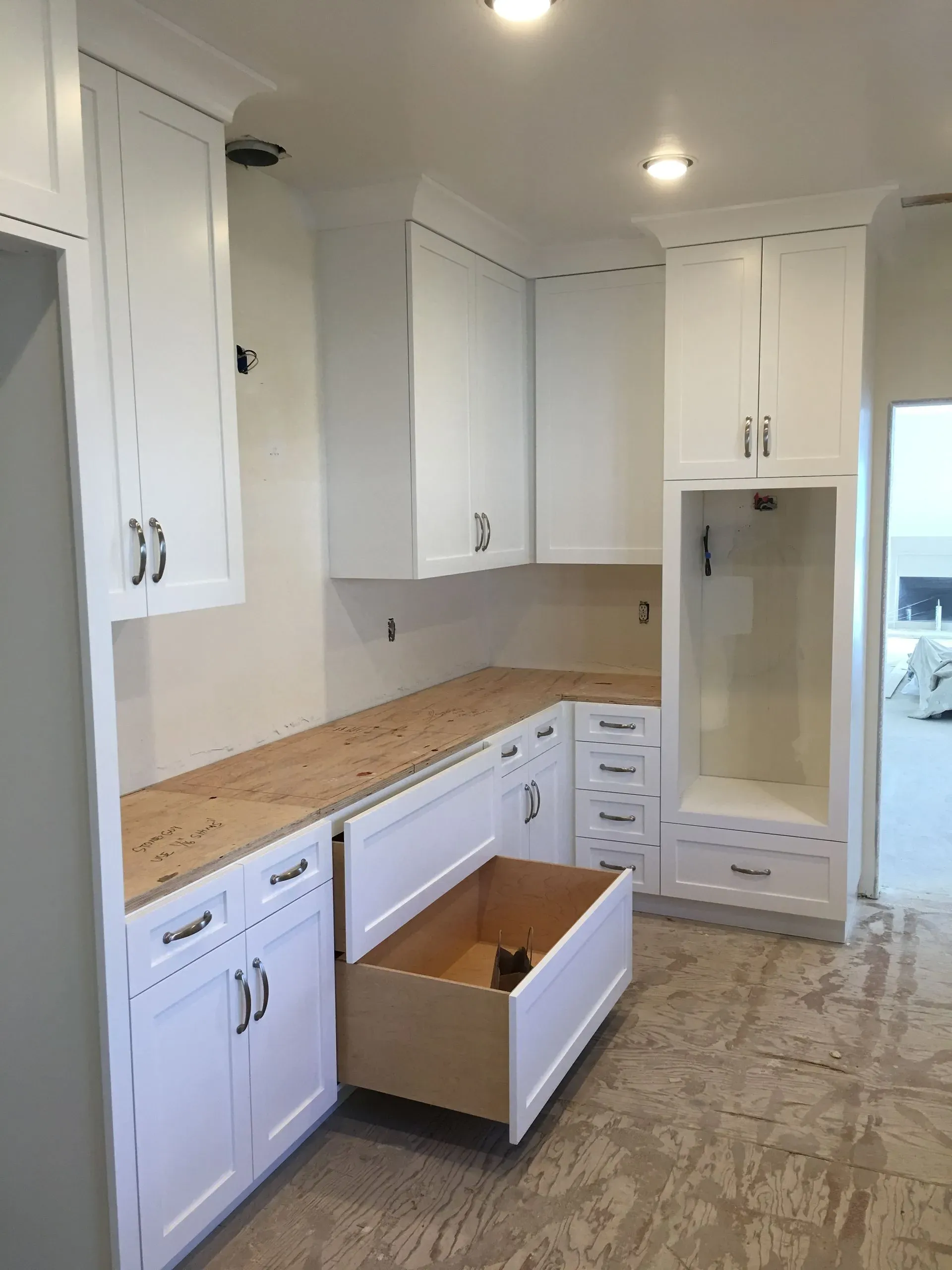 White kitchen with cabinets, wood countertop, and an open drawer on a tiled floor