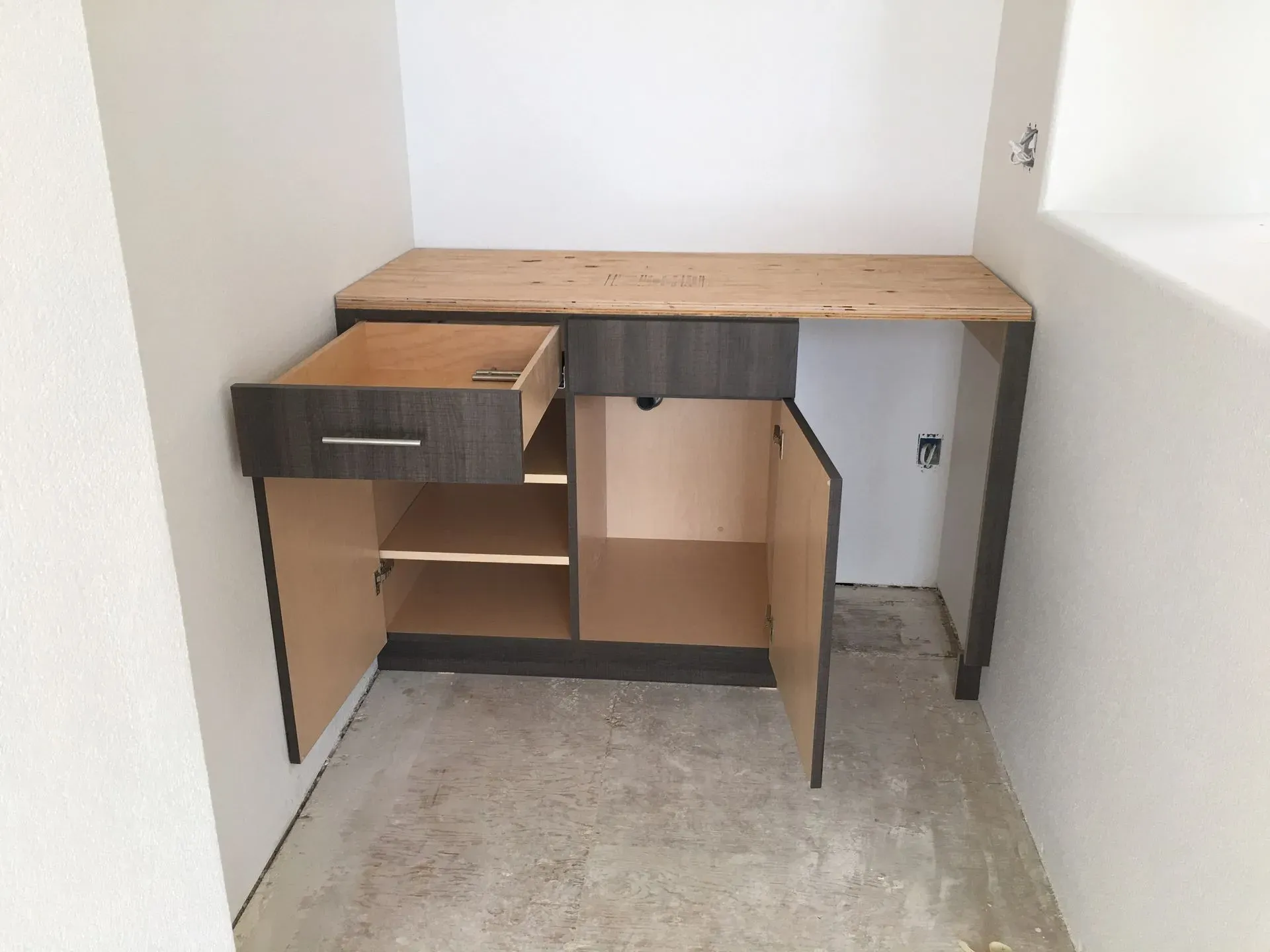 Corner desk with open cabinet doors and drawers in an empty room