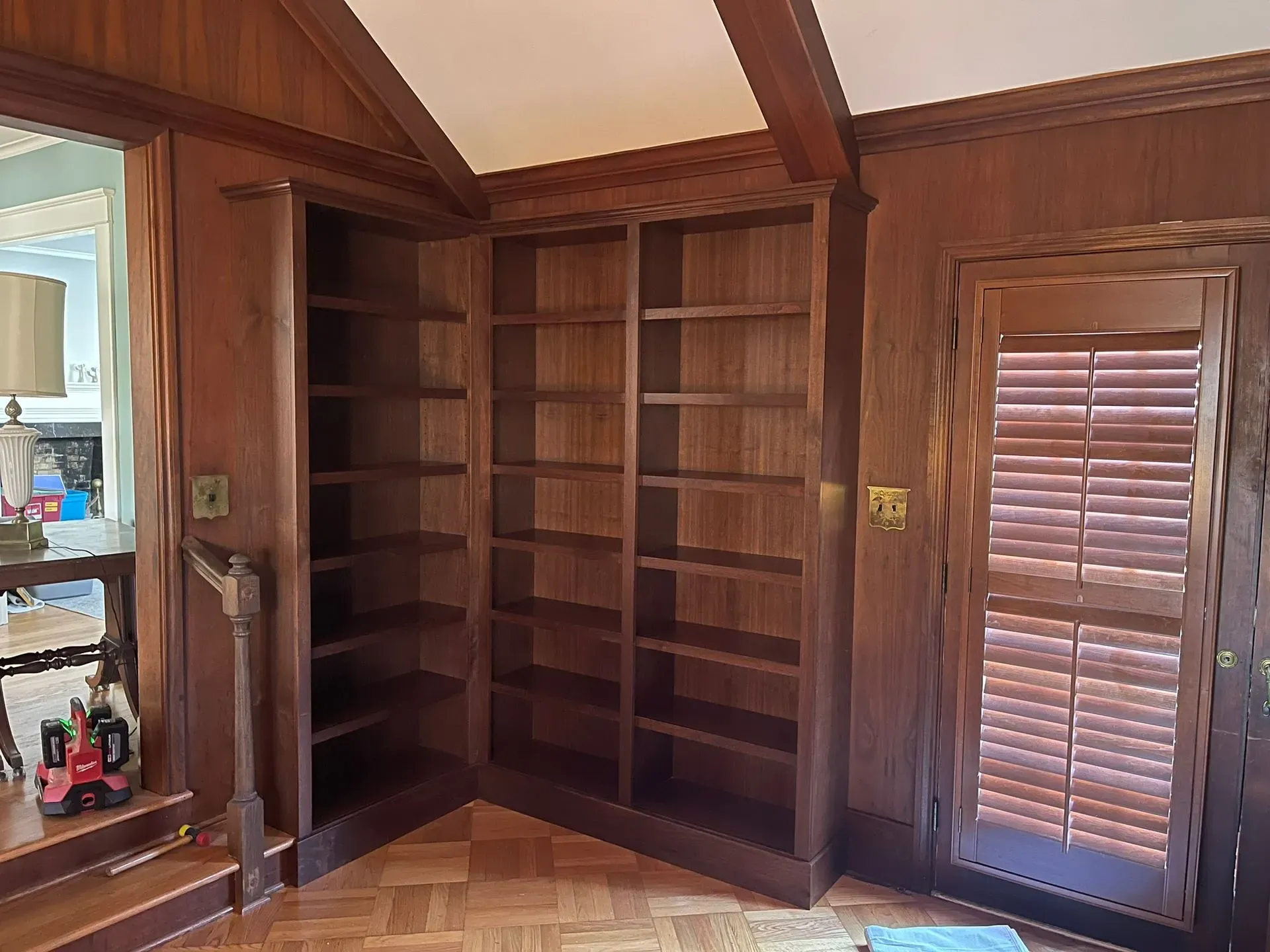 Wood-paneled room with built-in corner bookshelves and a closed louvered closet door.