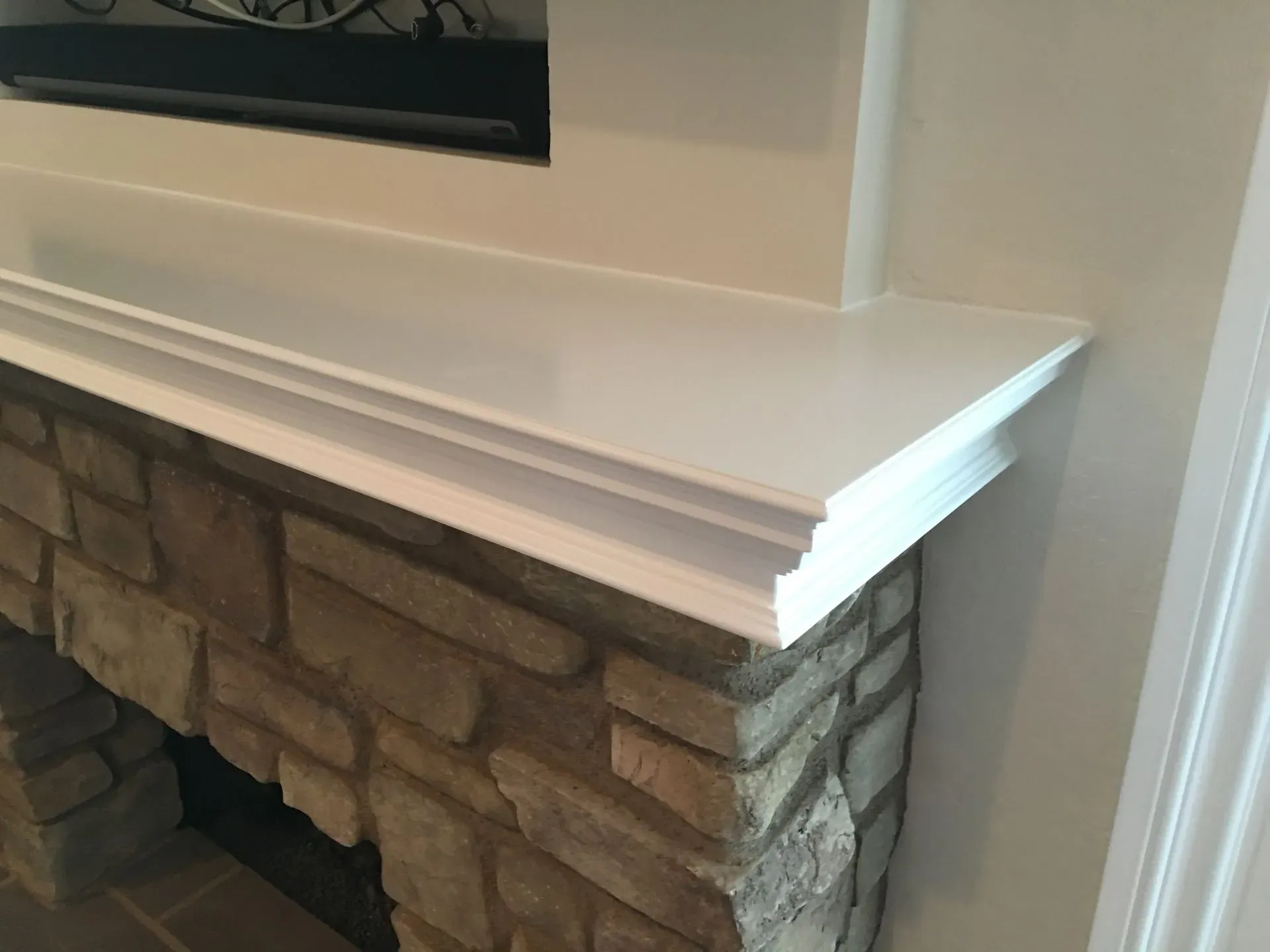 Stone fireplace with white mantel and trim beneath a wall-mounted TV