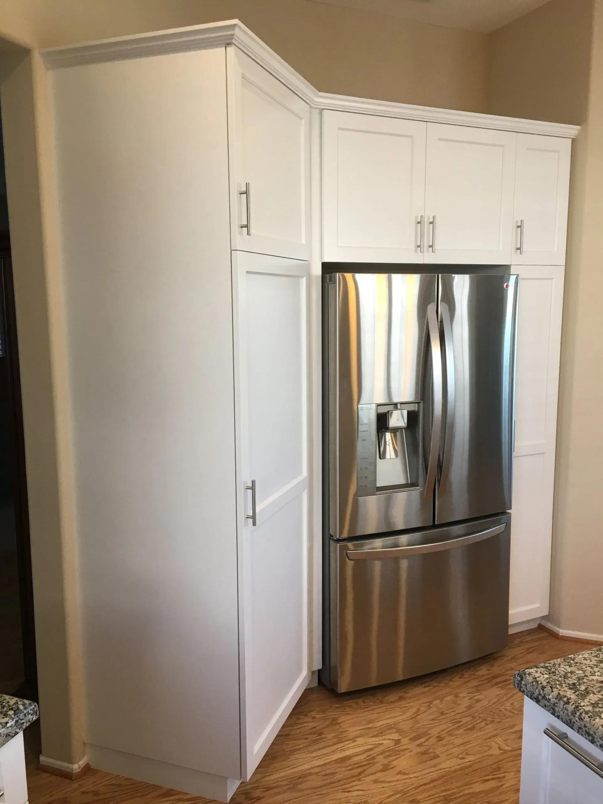 Kitchen corner with white cabinets and a stainless steel refrigerator next to a granite countertop.