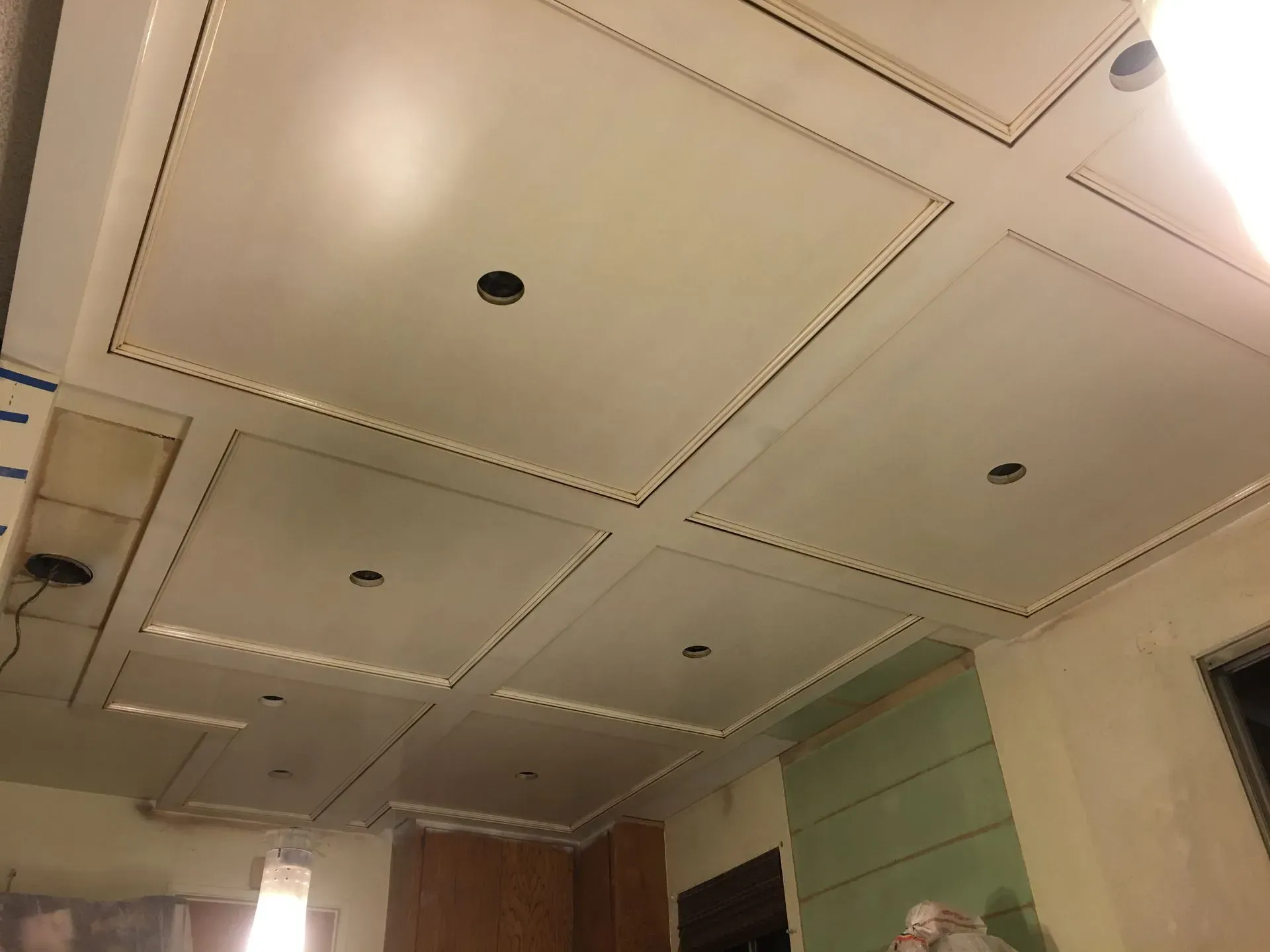 Ceiling with recessed panels and small round lights in an unfinished room