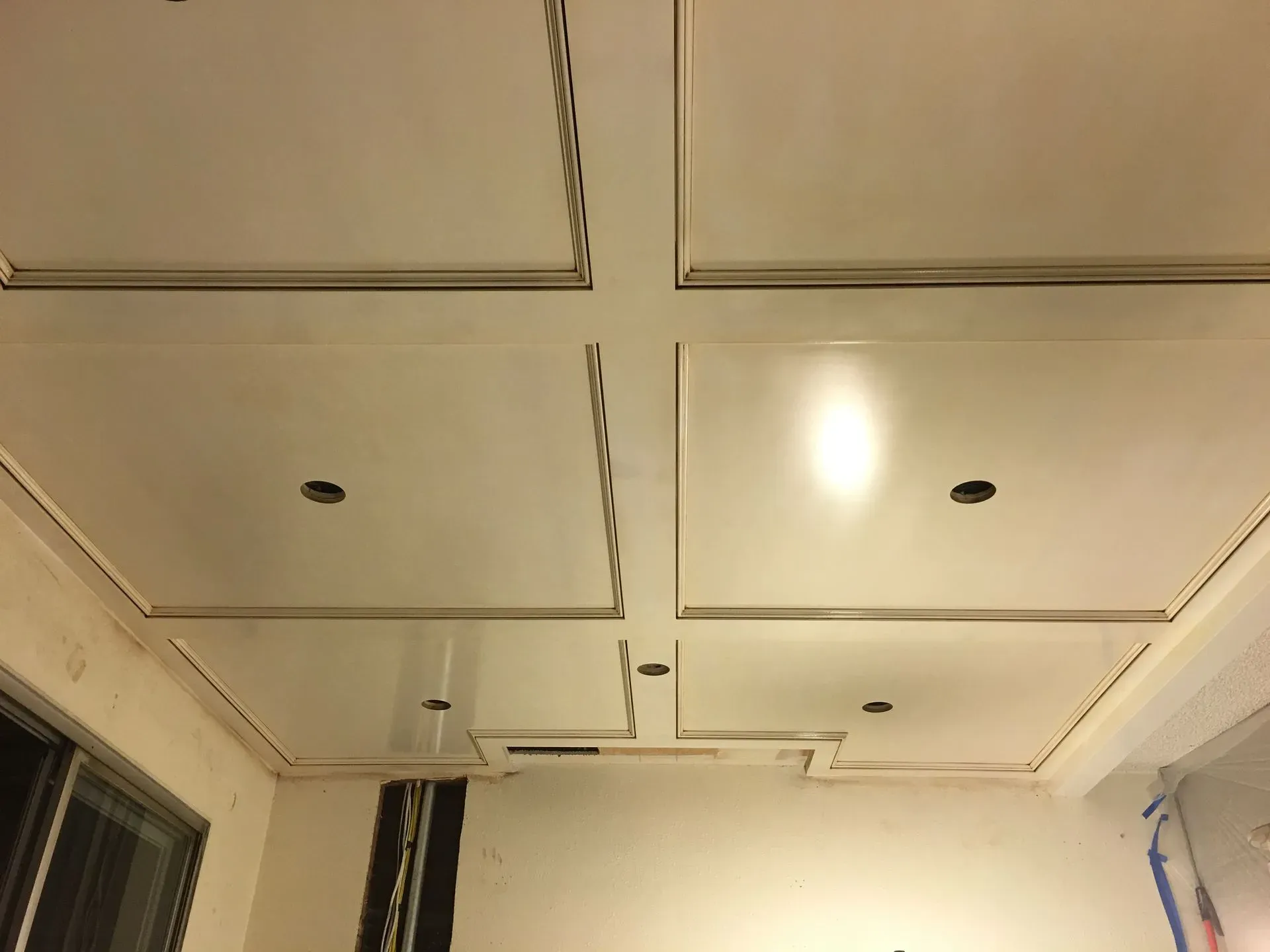 White coffered ceiling with recessed lights and a ceiling fan in a room
