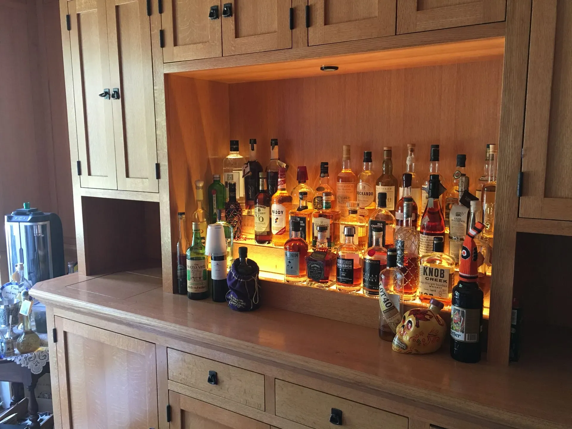 Backlit wooden cabinet with shelves of liquor bottles and a countertop