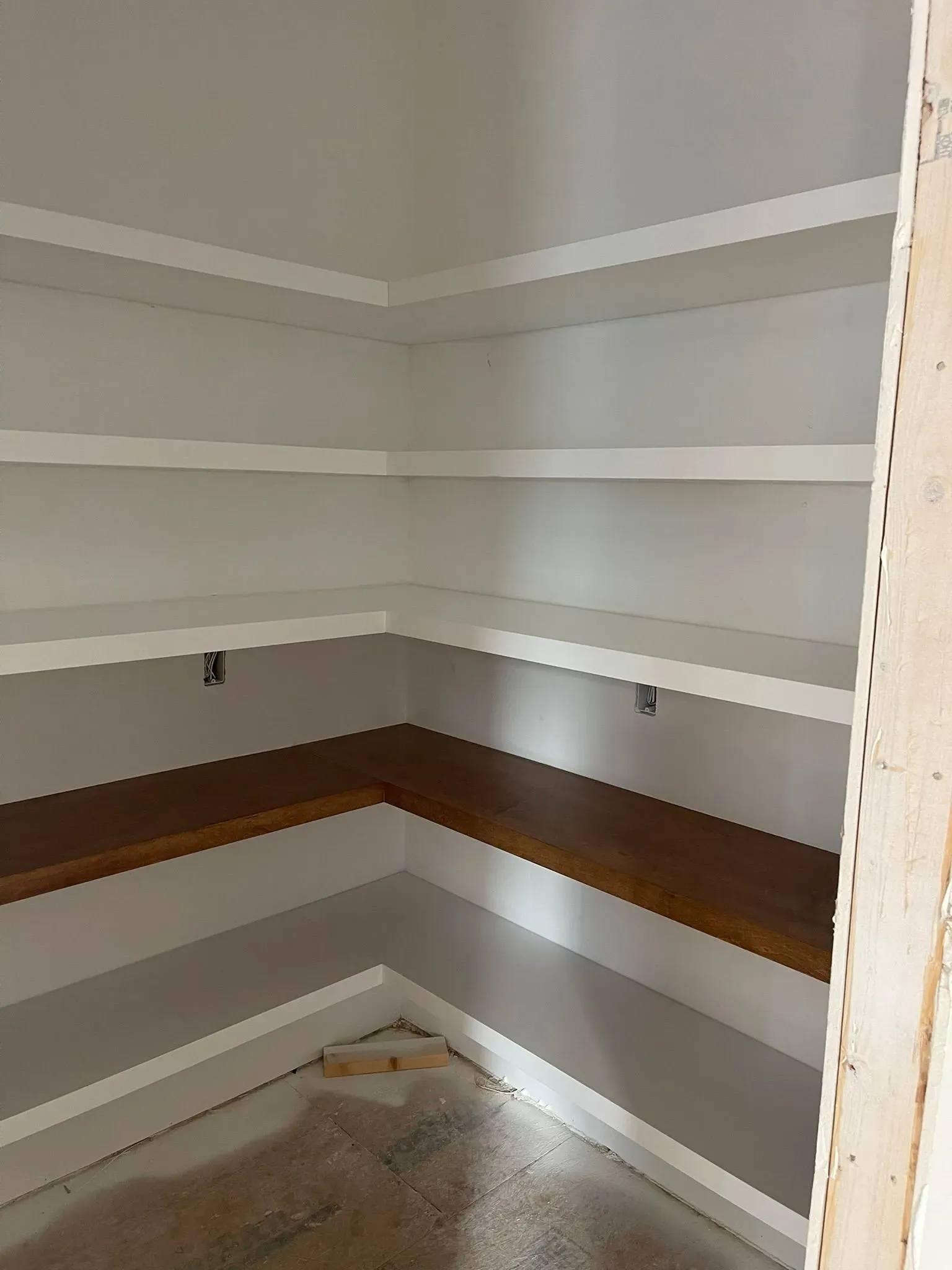 Empty walk-in closet with white shelves and a brown wraparound shelf along the walls