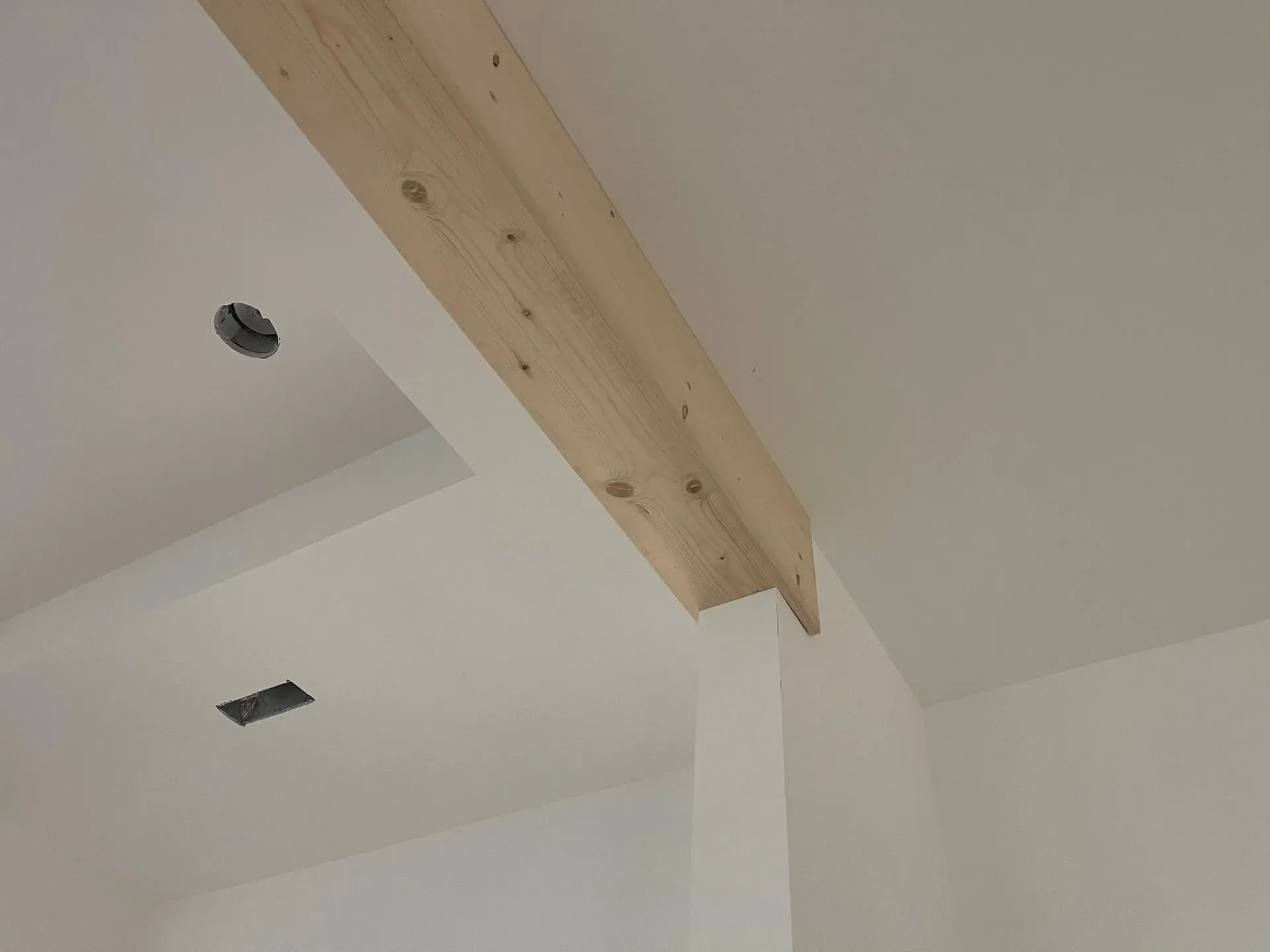 Interior ceiling with exposed wooden beam and recessed light openings