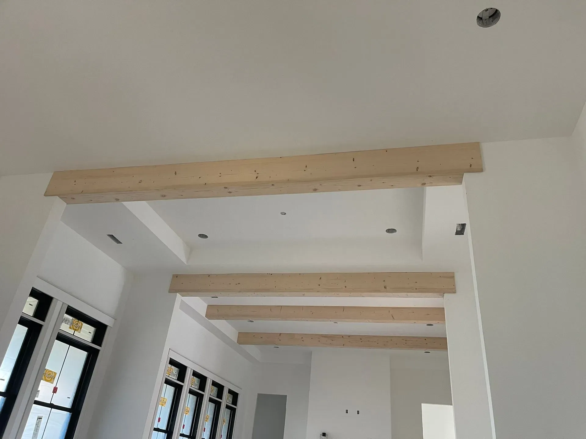 Interior with exposed wooden ceiling beams in a white room under construction.