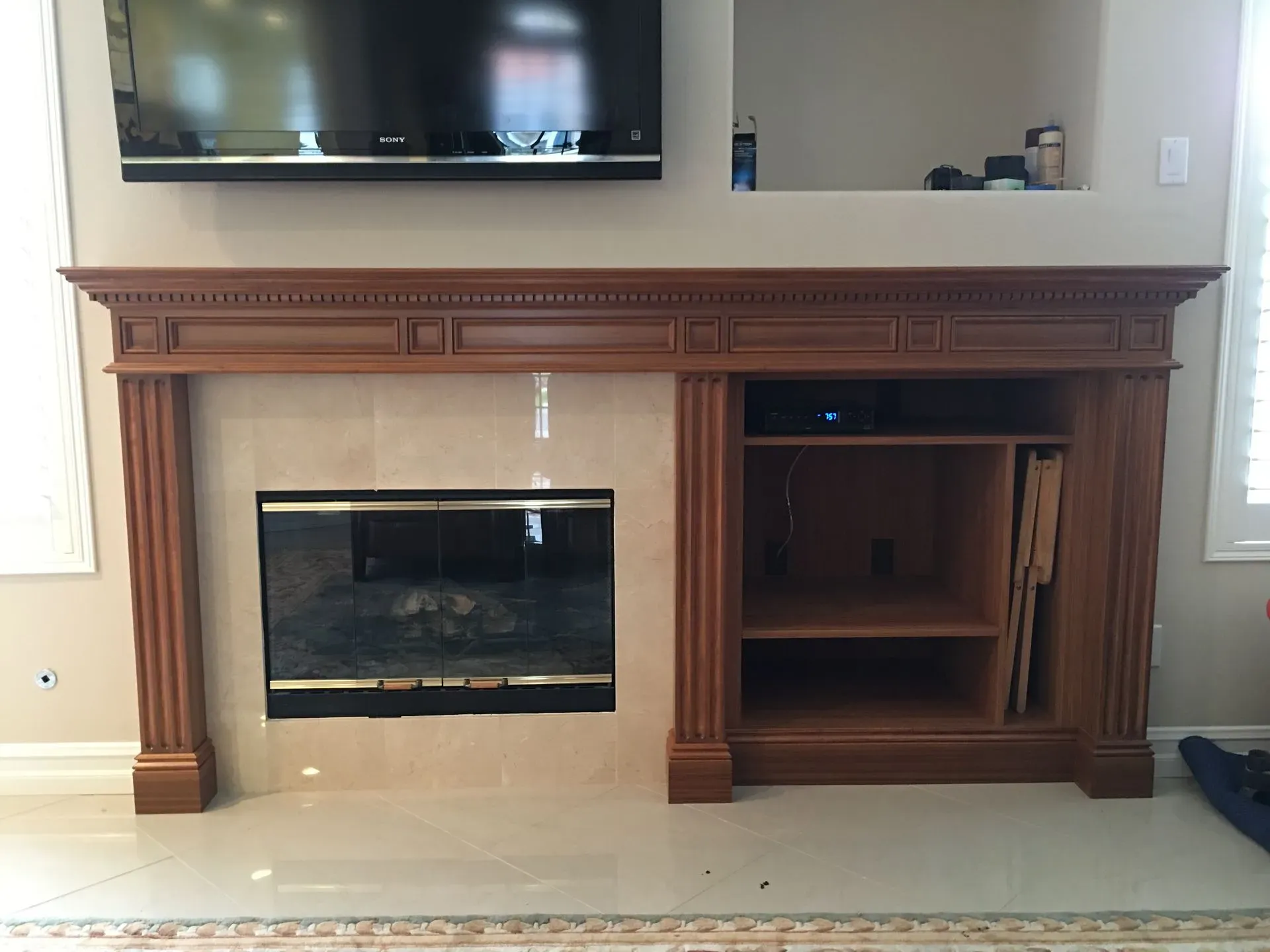 Living room fireplace with a wooden mantel and a TV mounted above it