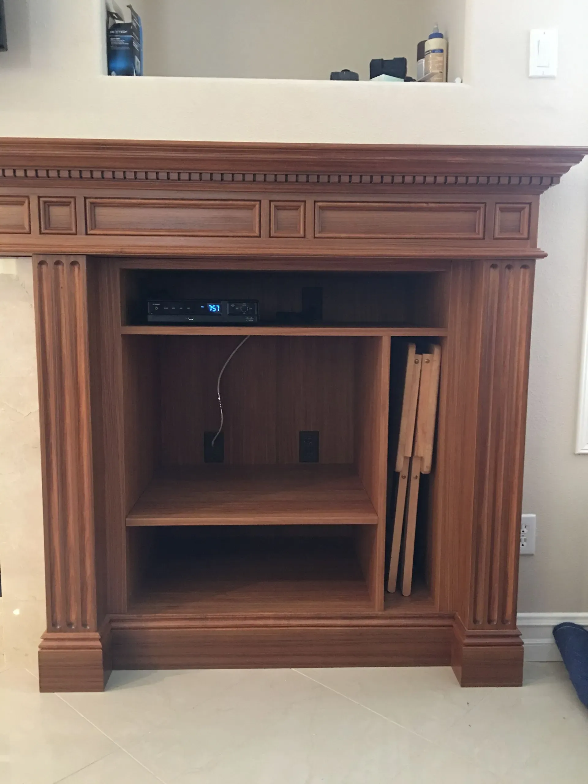 Wooden entertainment center with shelves and built-in fireplace opening in a living room.
