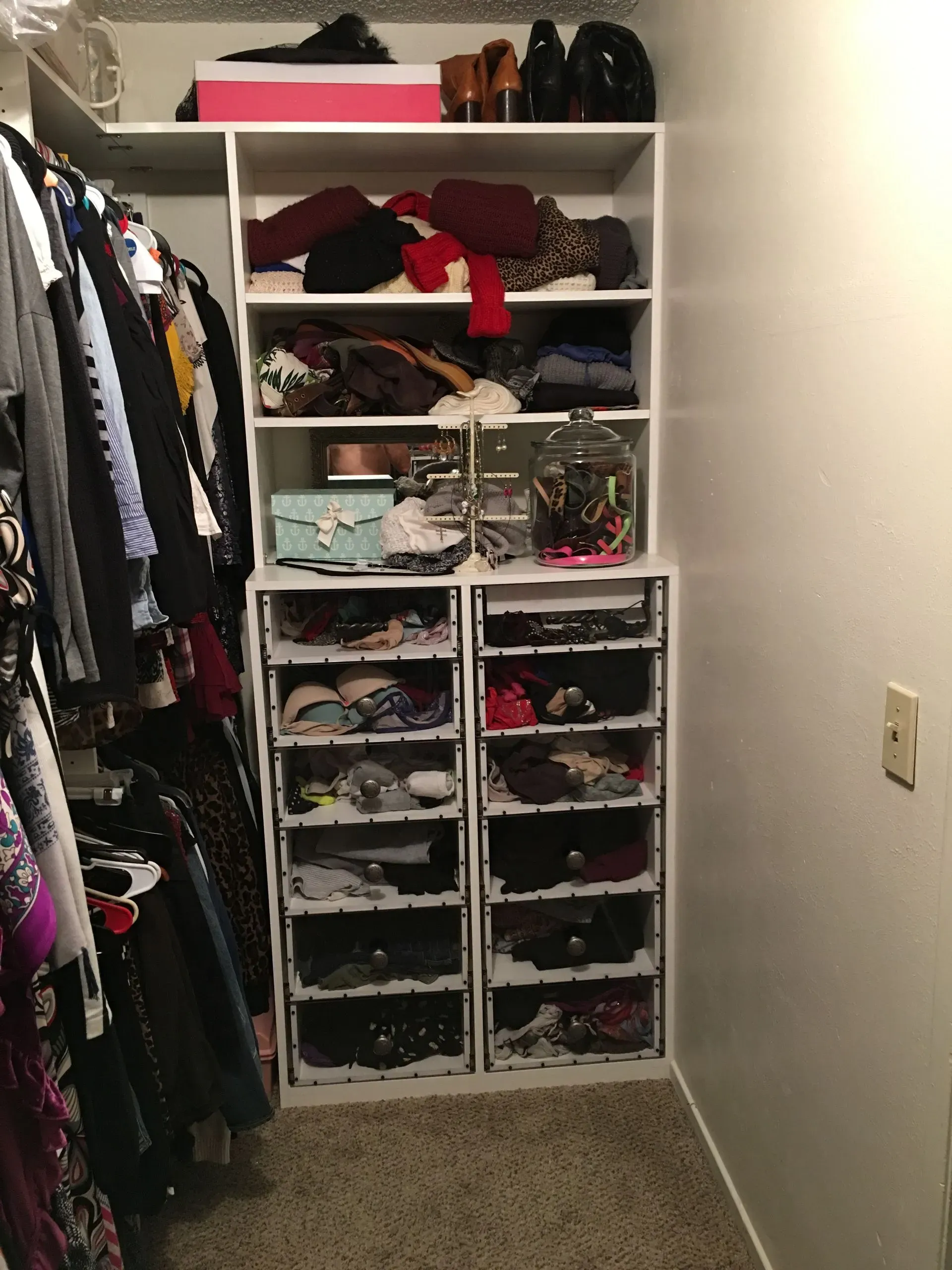 Small closet with hanging clothes and shelves of folded clothes and storage bins.