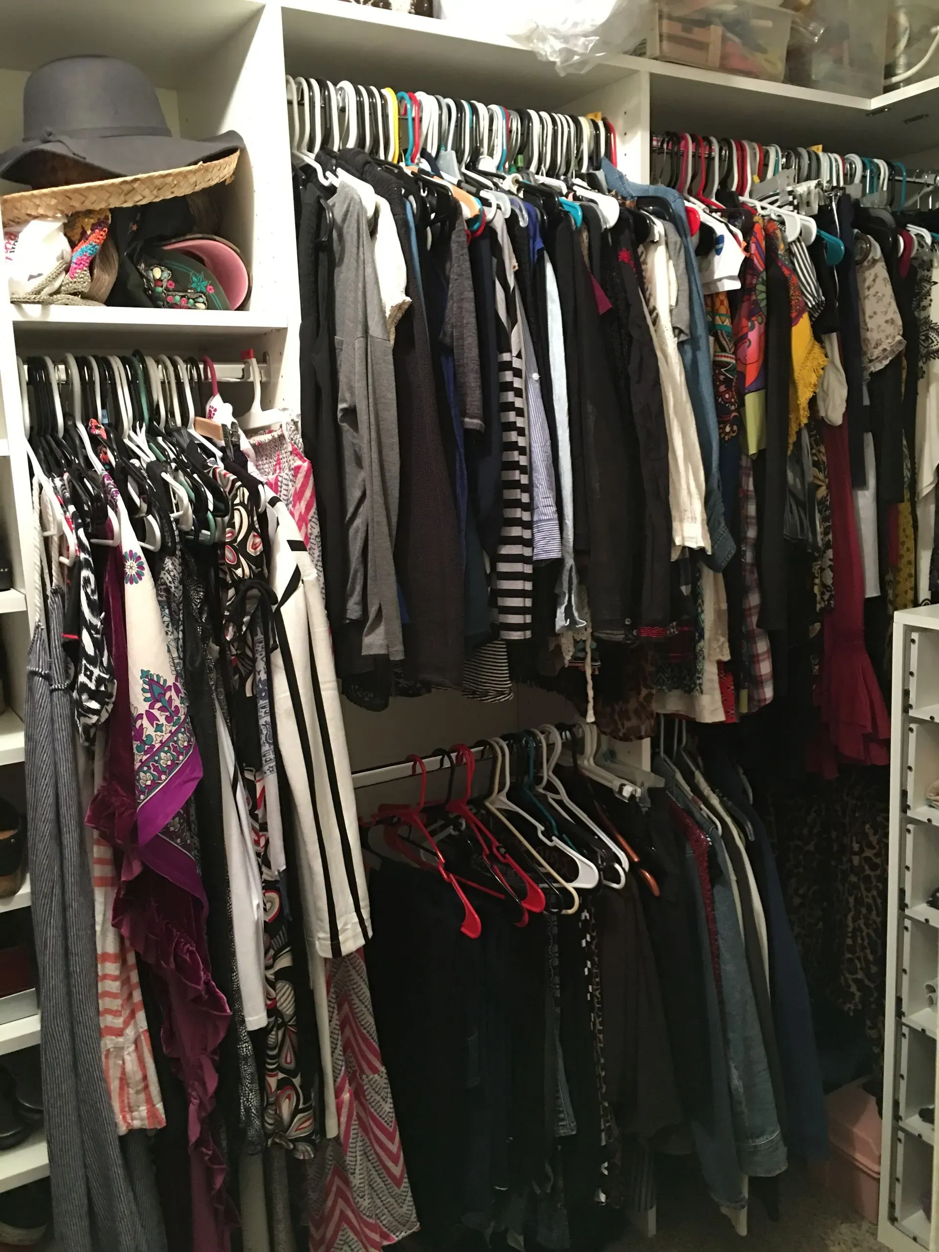 Closet with two packed clothing racks and shelves, filled with assorted dresses, tops, and hats.