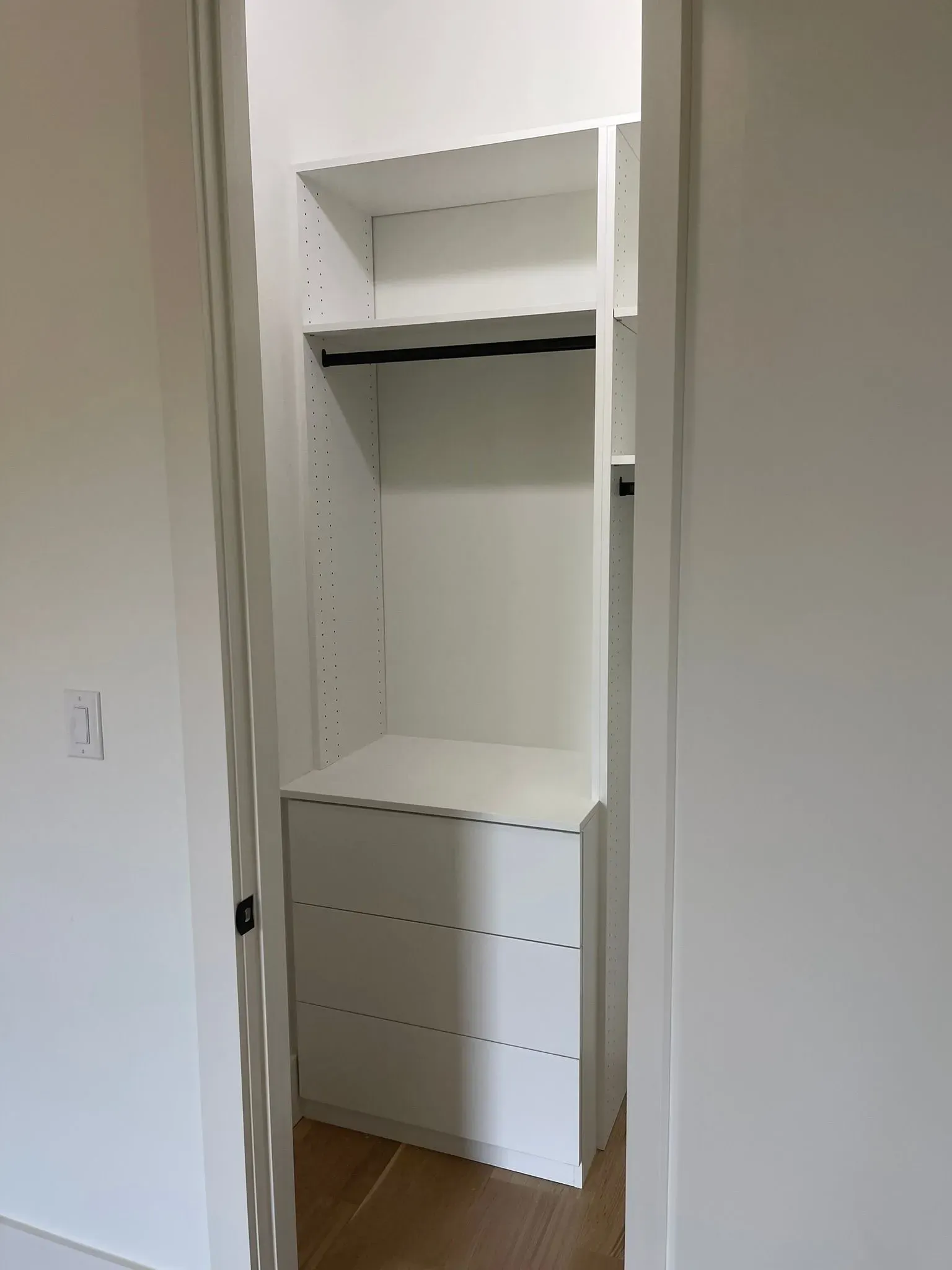 White built-in closet with open hanging space and drawers in a room.