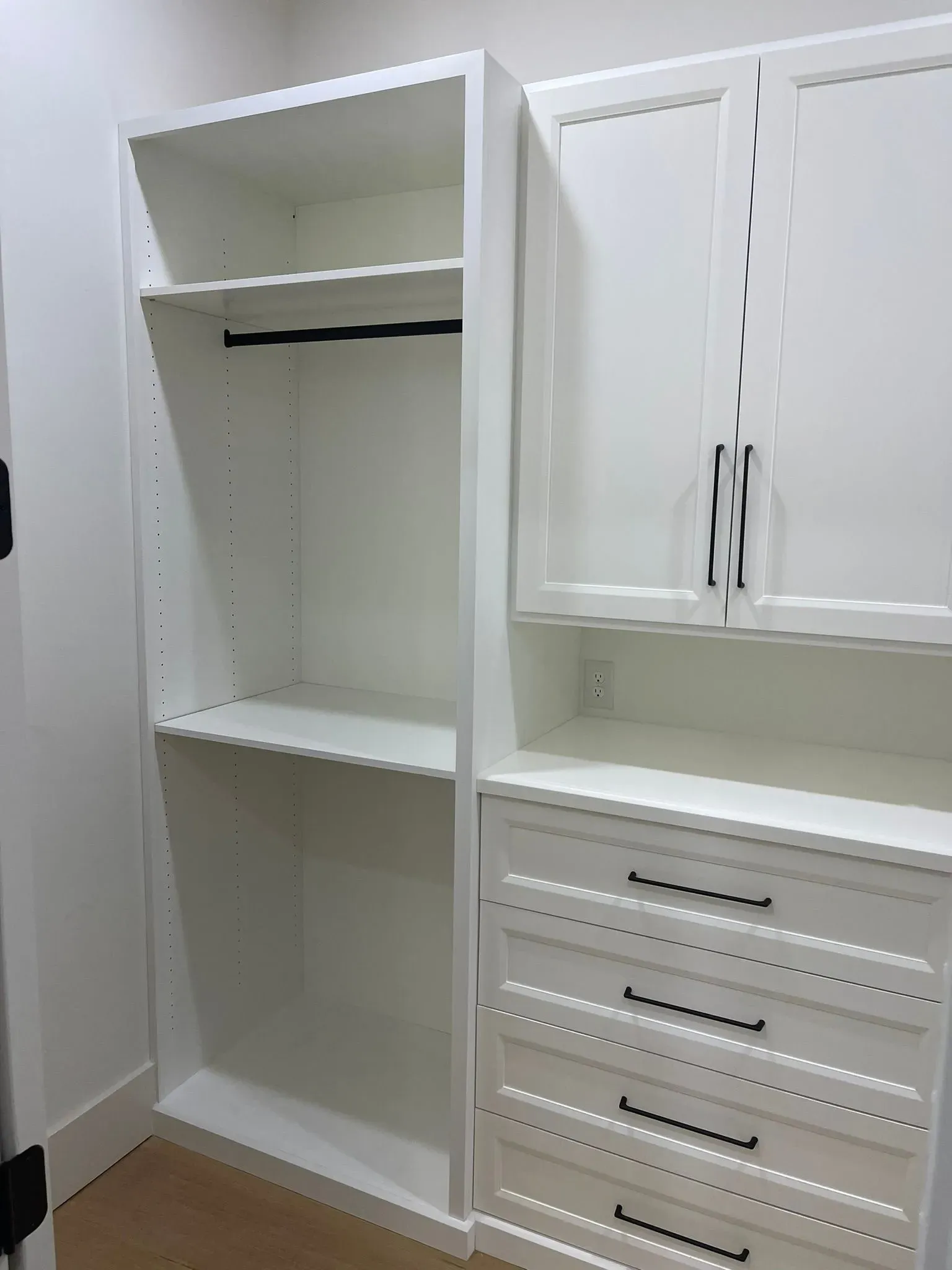 White closet and dresser unit with open shelving, hanging rod, cabinet doors, and drawers in a room