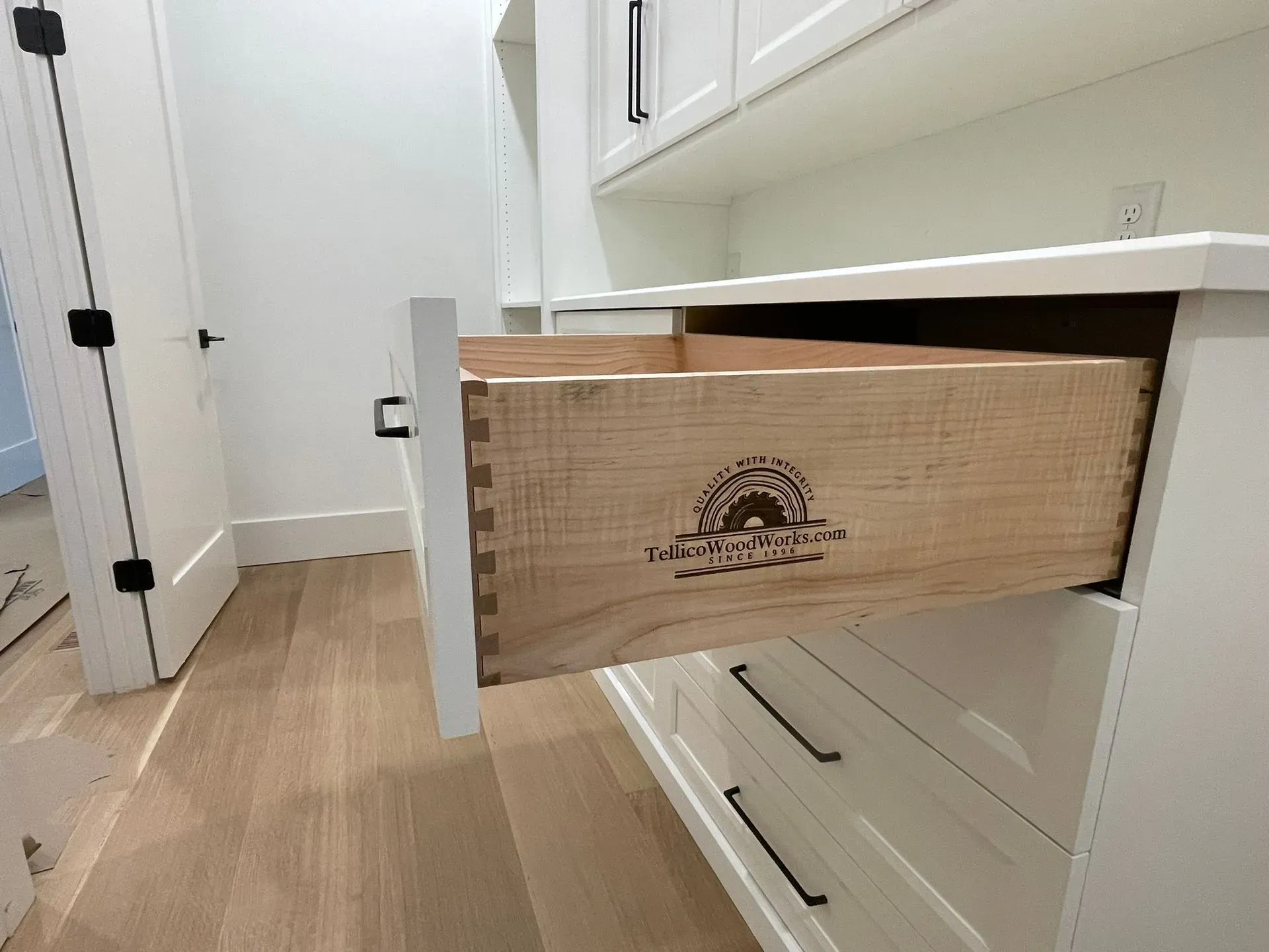A kitchen drawer is pulled open, revealing a cardboard box inside.