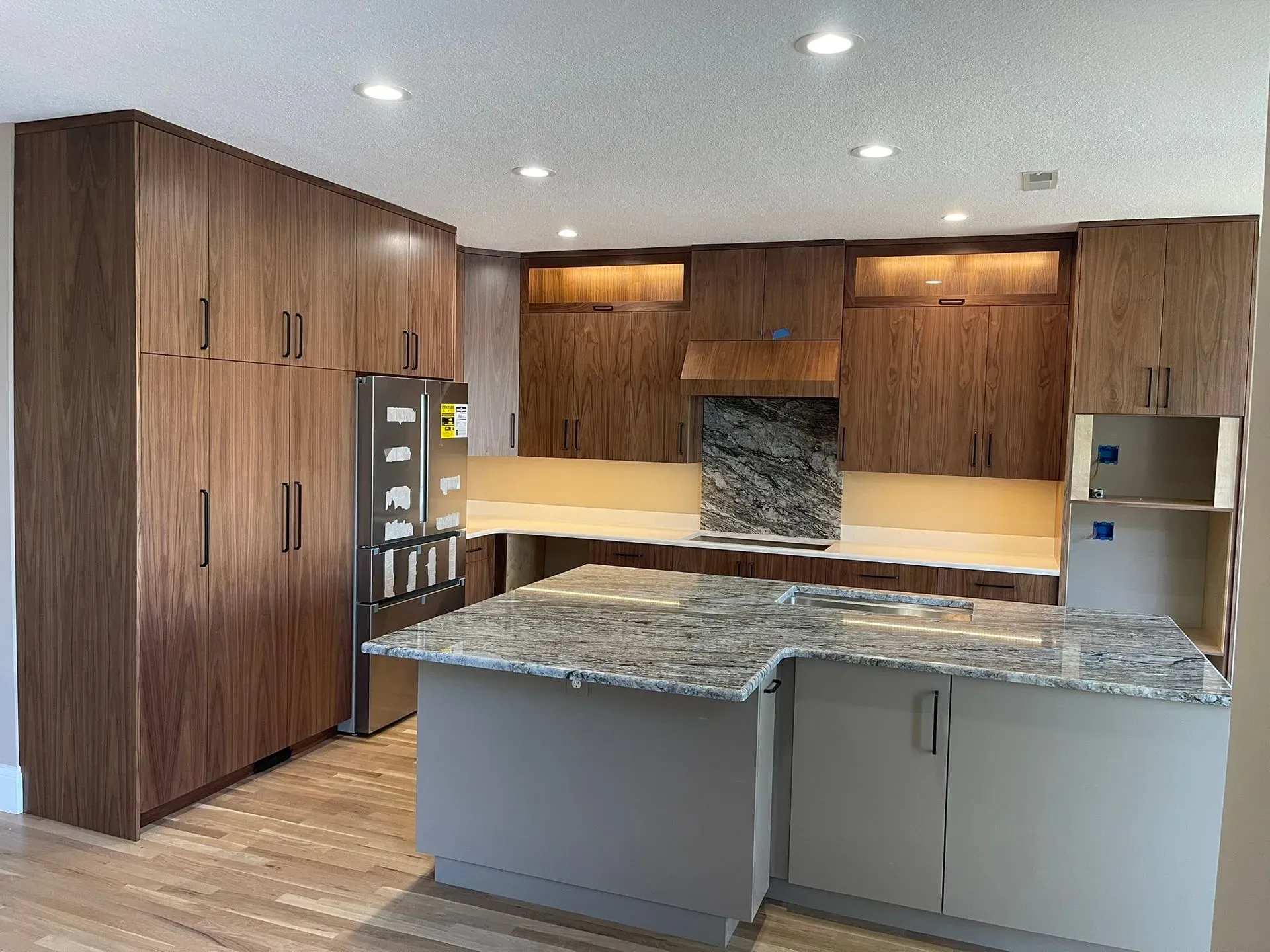 Modern kitchen with wood cabinets, granite island, stainless appliances, and recessed lighting.