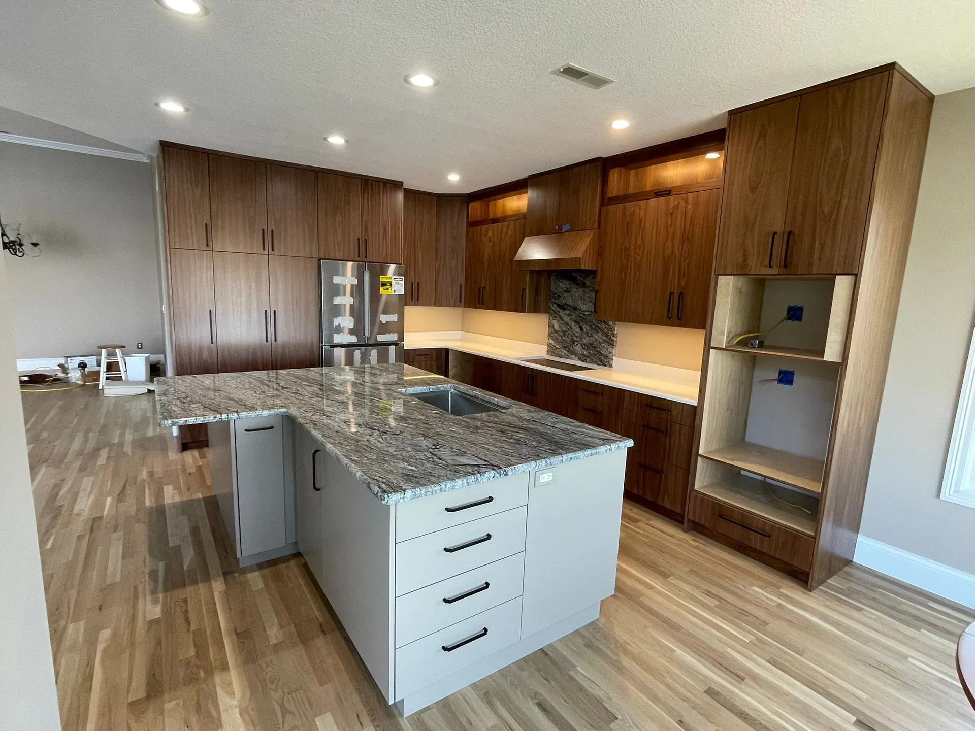 Modern kitchen with wood cabinets, granite island, stainless fridge, and built-in appliances