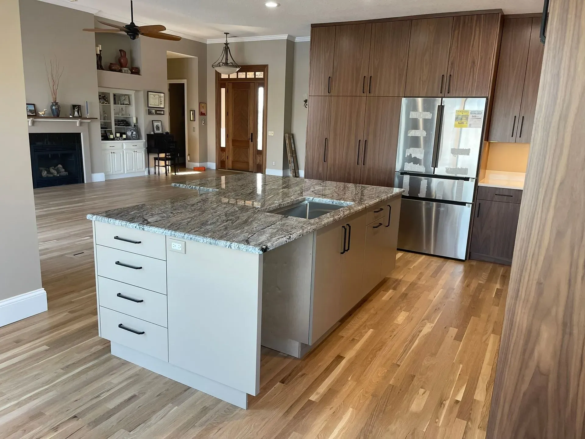 Bright modern kitchen with granite island, hardwood floors, and stainless steel refrigerator