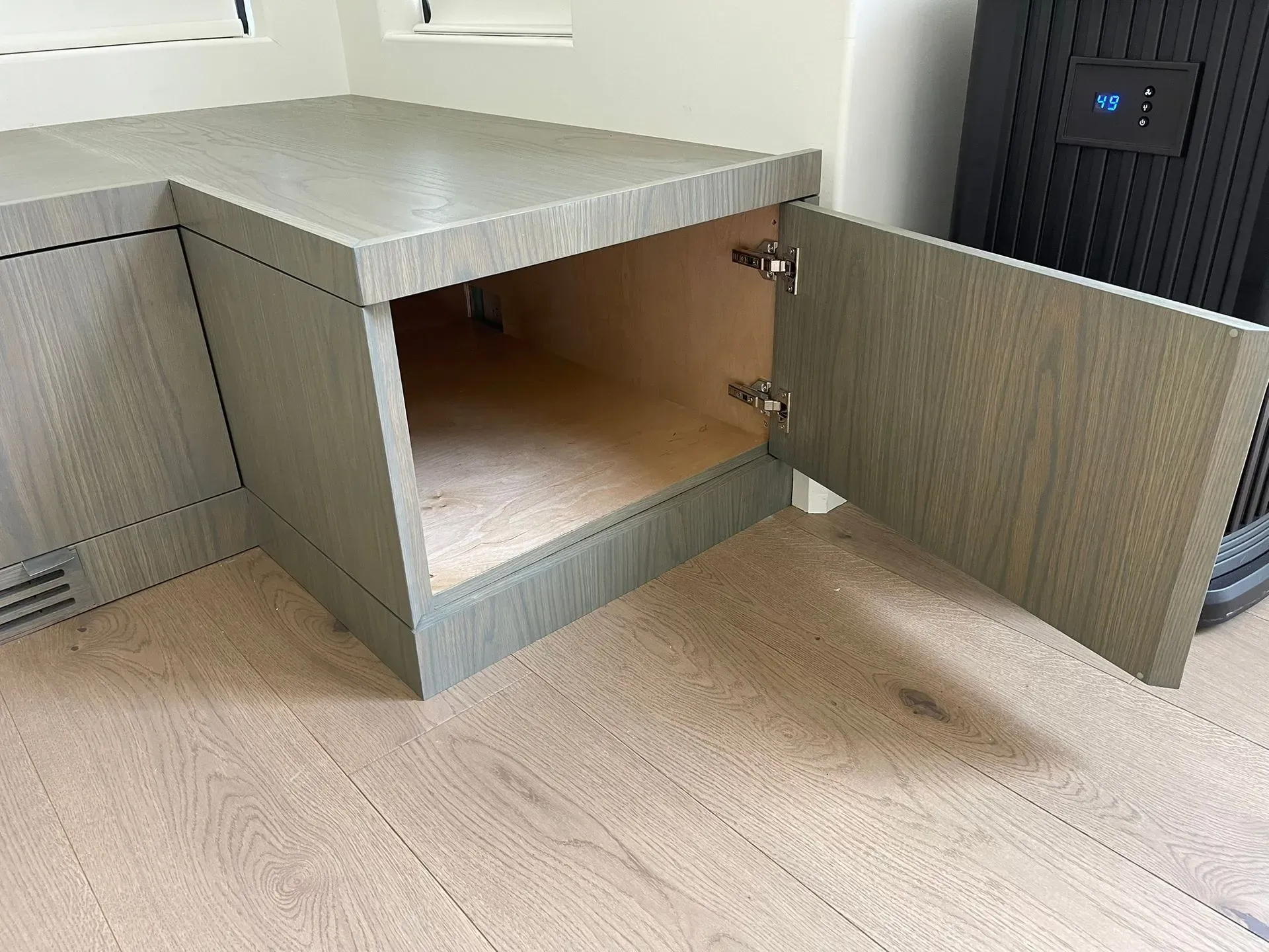 Open cabinet with gray doors in a light wood-floored room
