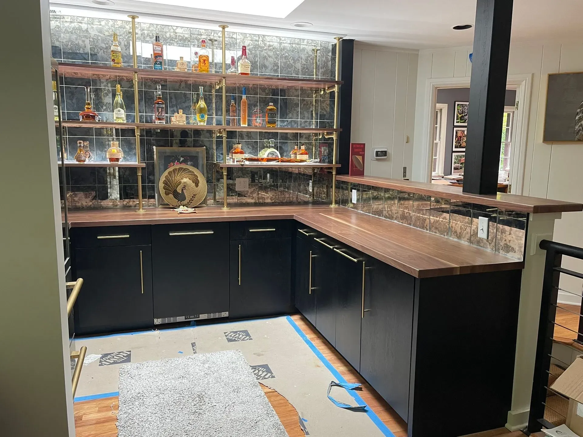 Home bar with black cabinets, granite countertop, mirrored shelves, and assorted glassware and bottles