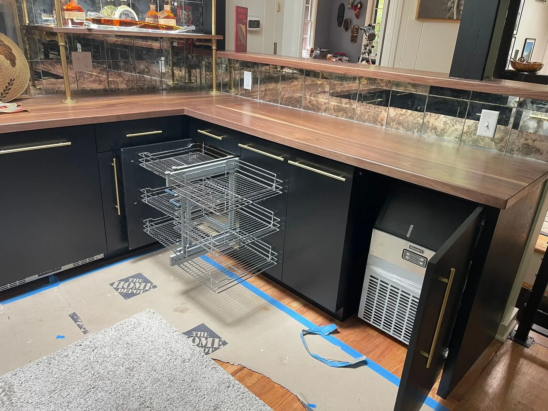 Kitchen with open dishwasher drawers under a marble countertop and dark cabinets.