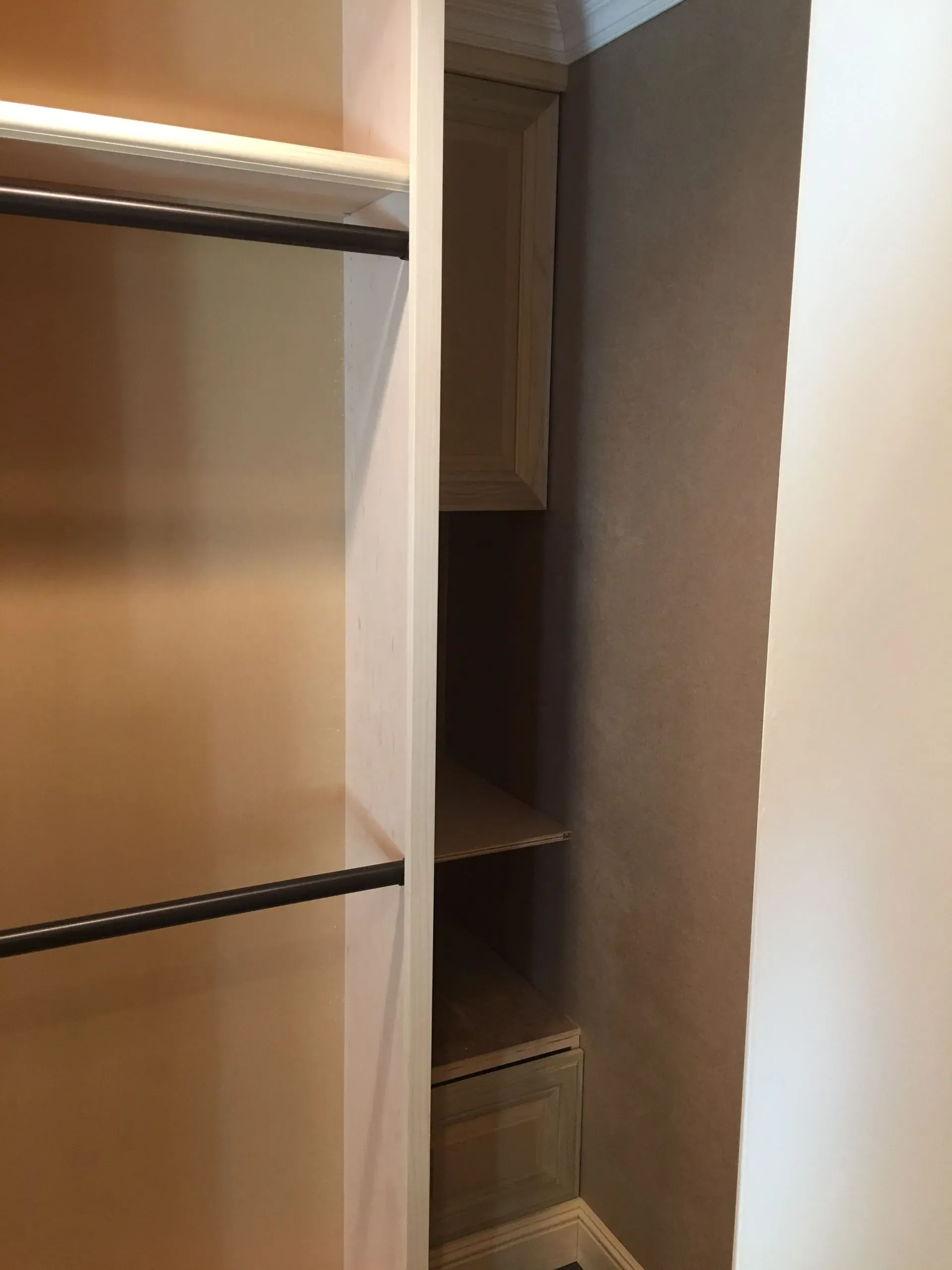 Open closet with empty shelves, hanging rod, and built-in storage in a beige room.