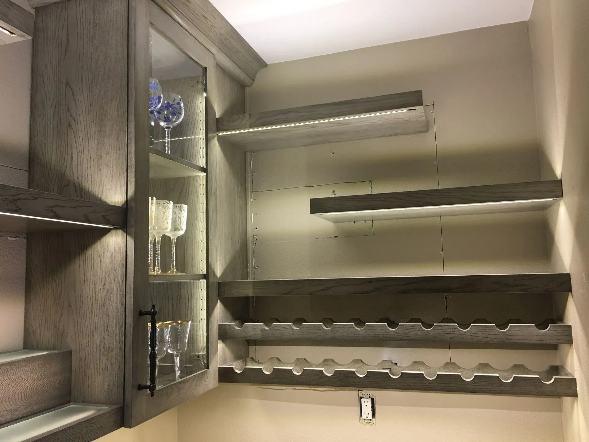 Open kitchen cabinet with shelves, stemware, and rack for wine glasses
