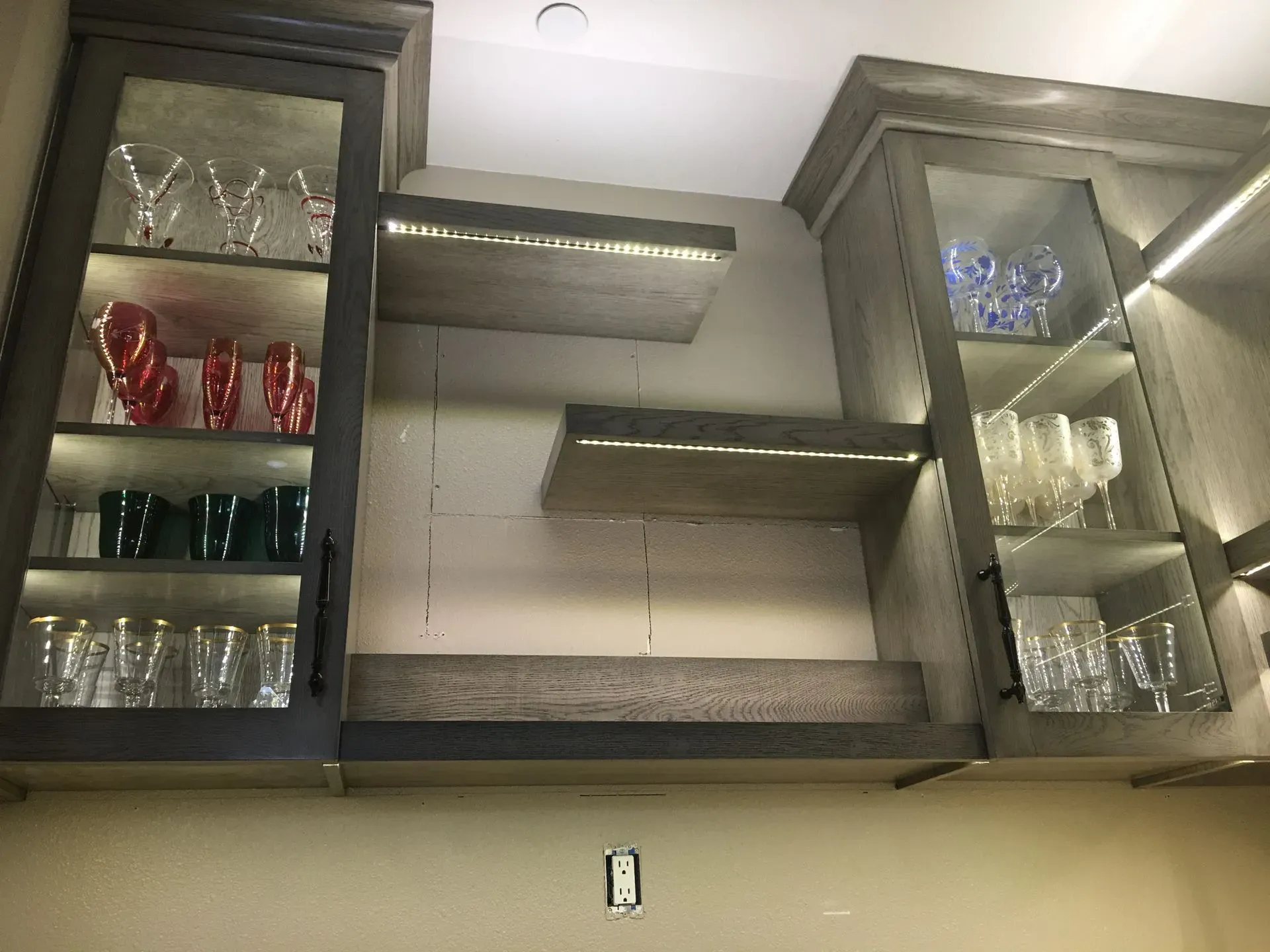 Kitchen cabinets with glassware and red mugs, open shelves, and a light-colored tile backsplash