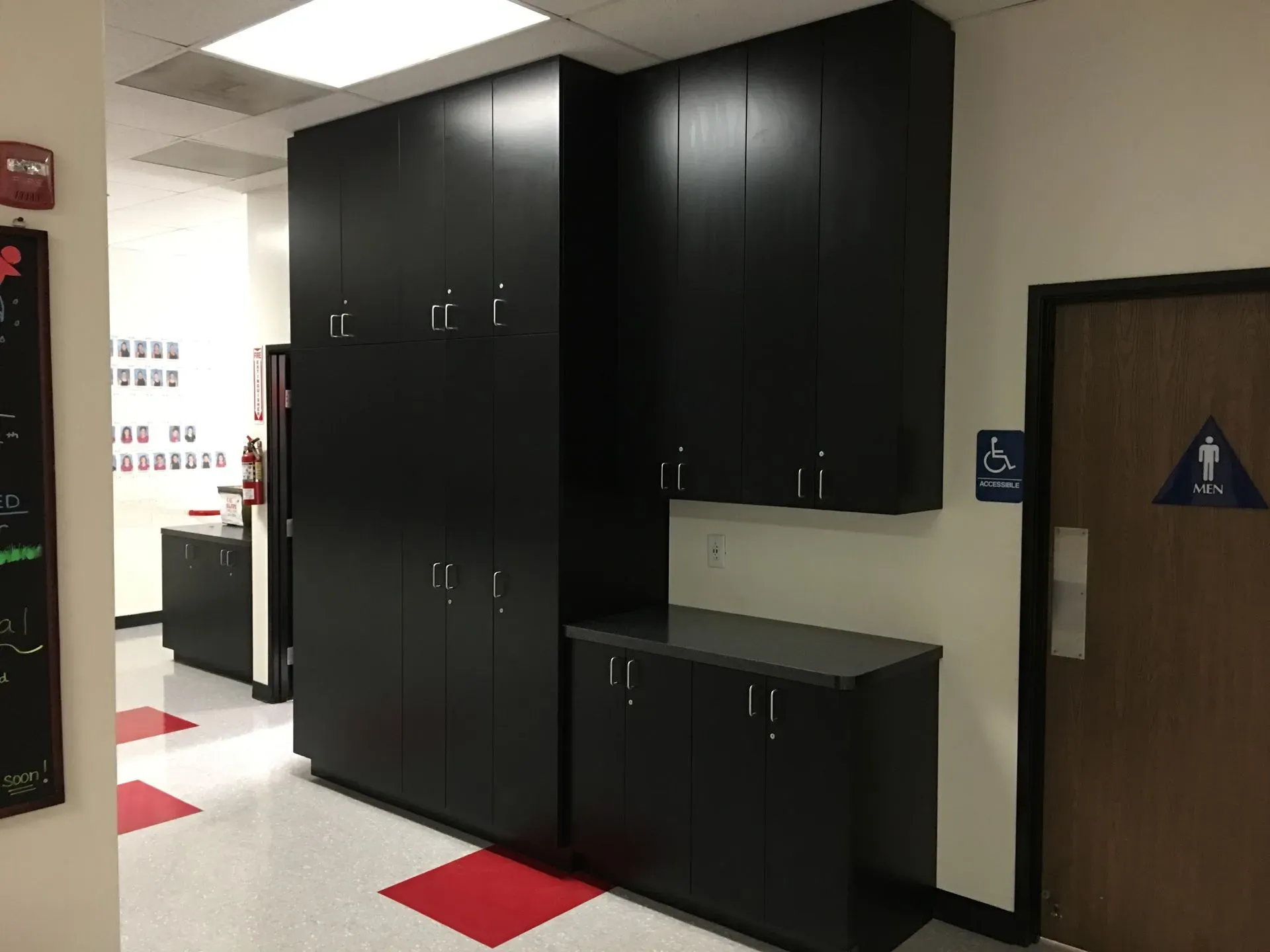 Hallway with black cabinets and a small sink area beside a restroom door